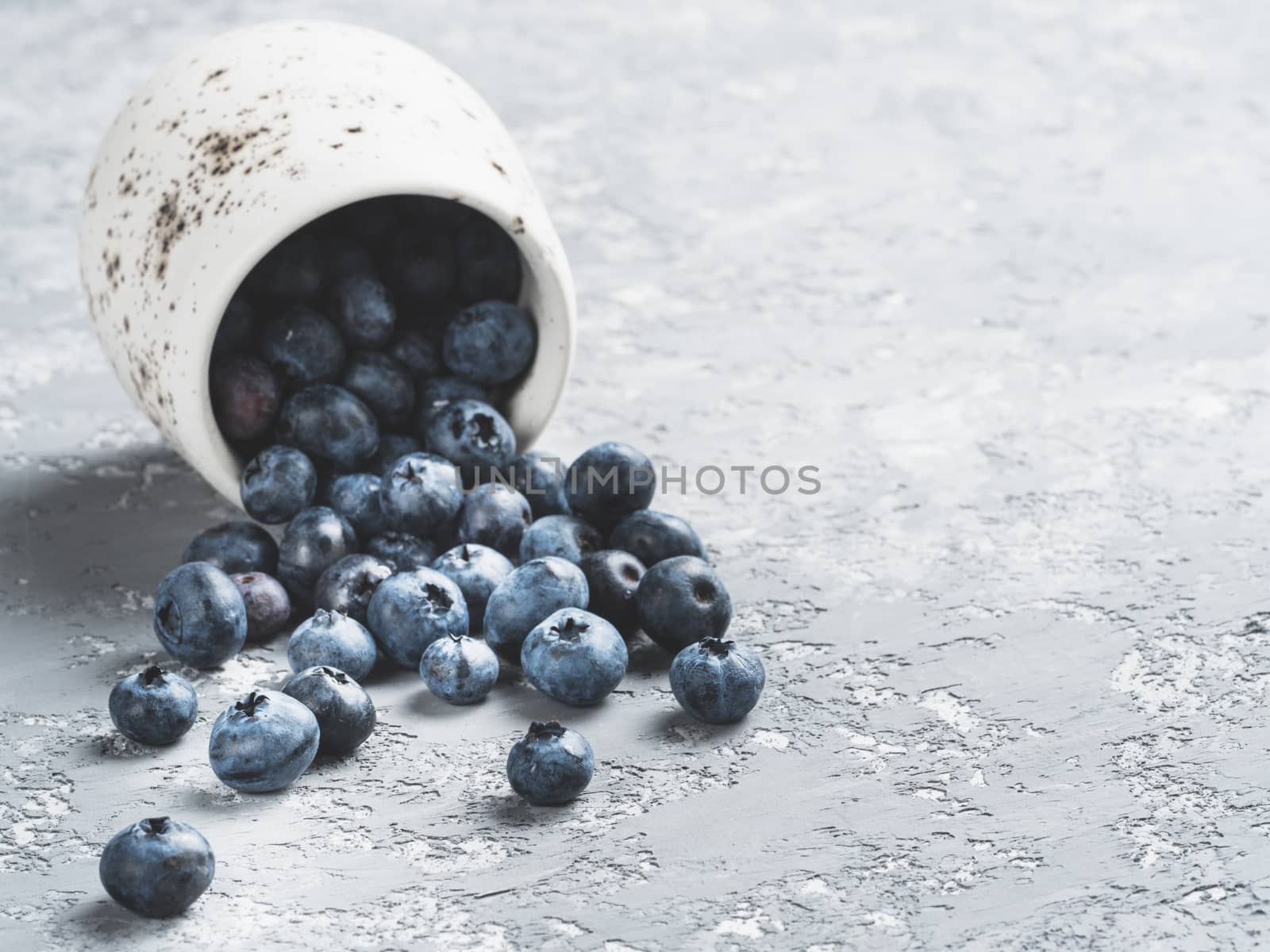 Blueberries on gray concrete background. Blueberry border design. Fresh picked bilberries scattered close up. Copyspace. Closeup