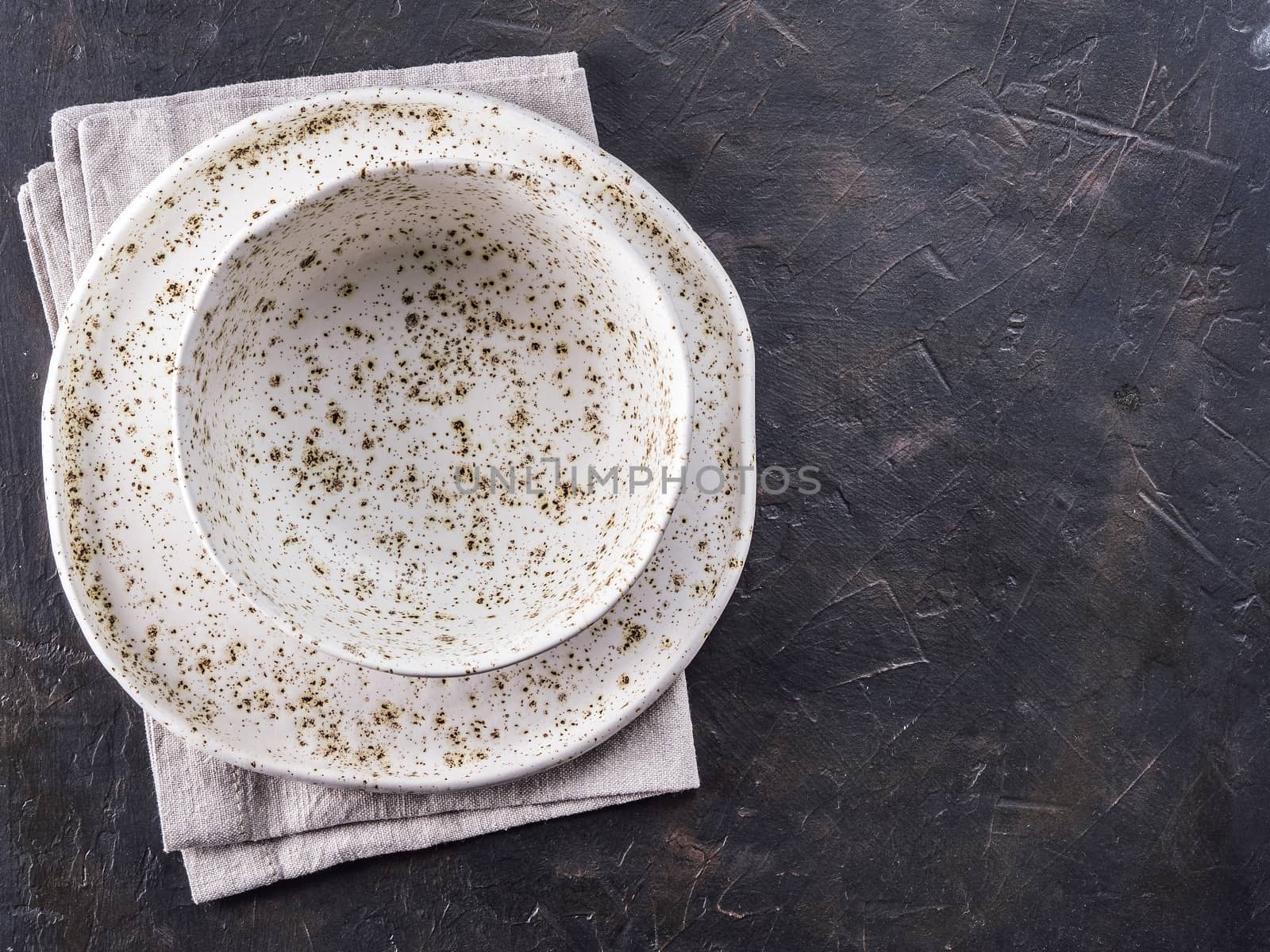 Table setting. White craft plate at dark slate table. Dark food background. Top view copy space.