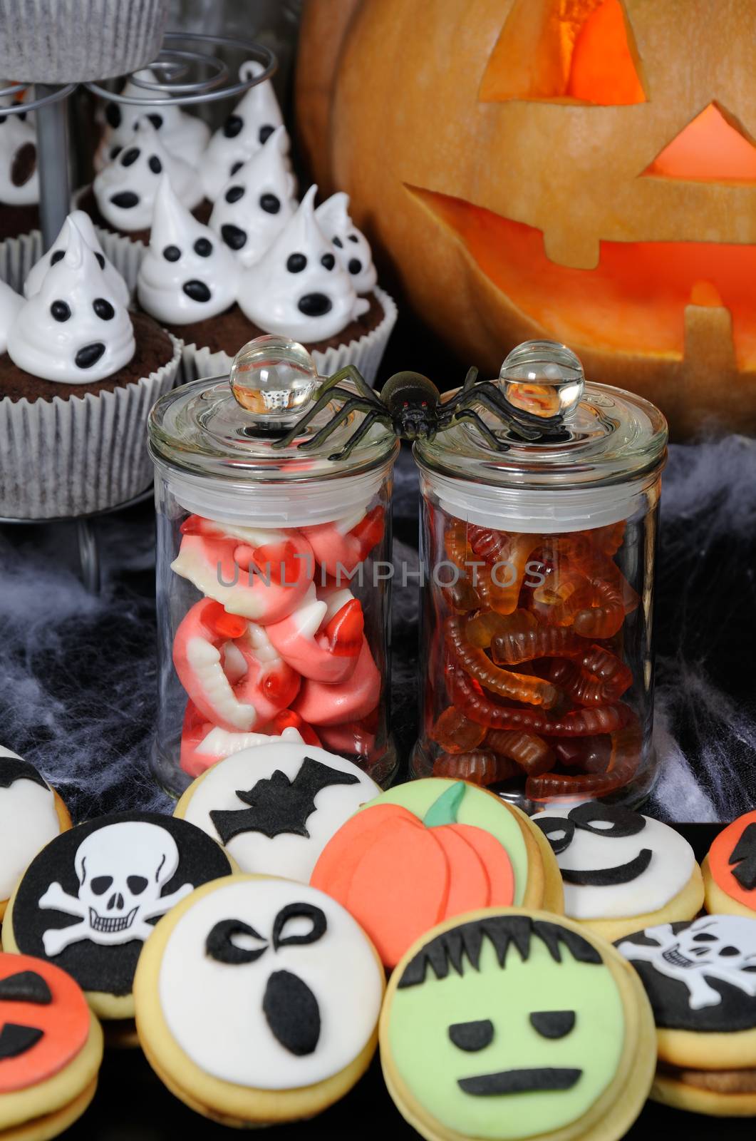 Jelly candies in the form of jaws and worms in a jar on a Halloween table among other sweets