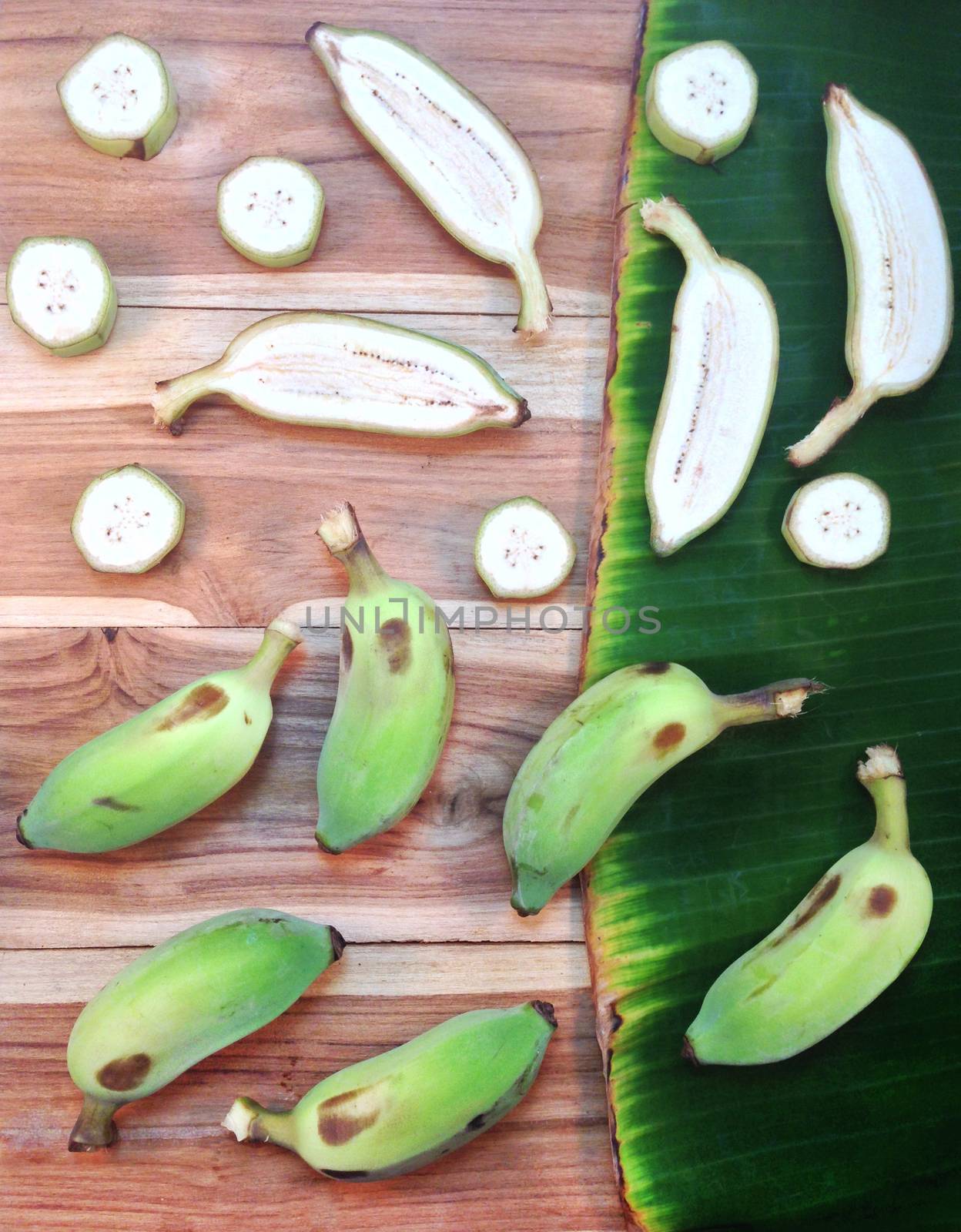 Green cultivated banana and piece of slices on wooden and banana by Bowonpat