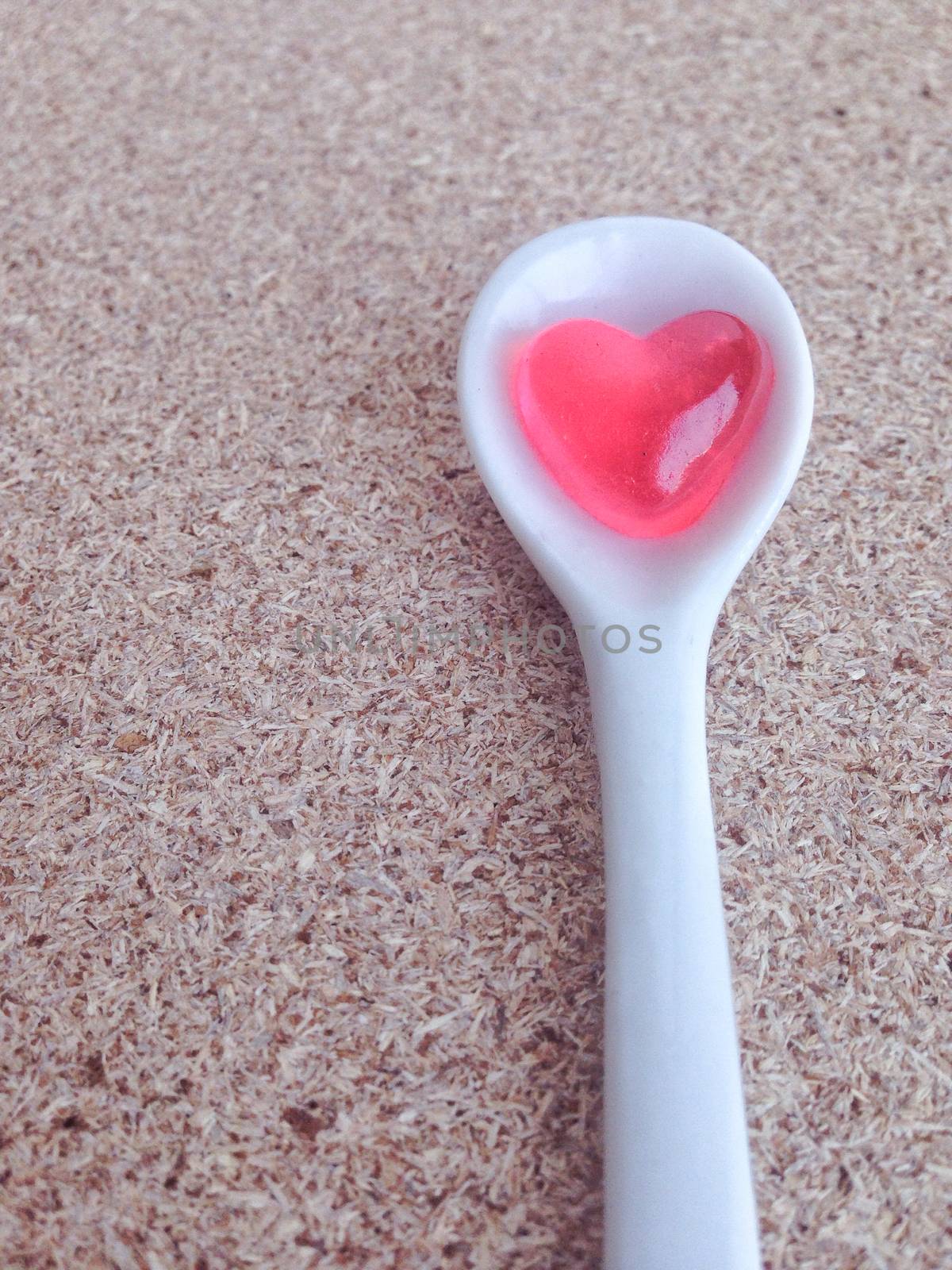 Mini heart in white little spoon on plywood