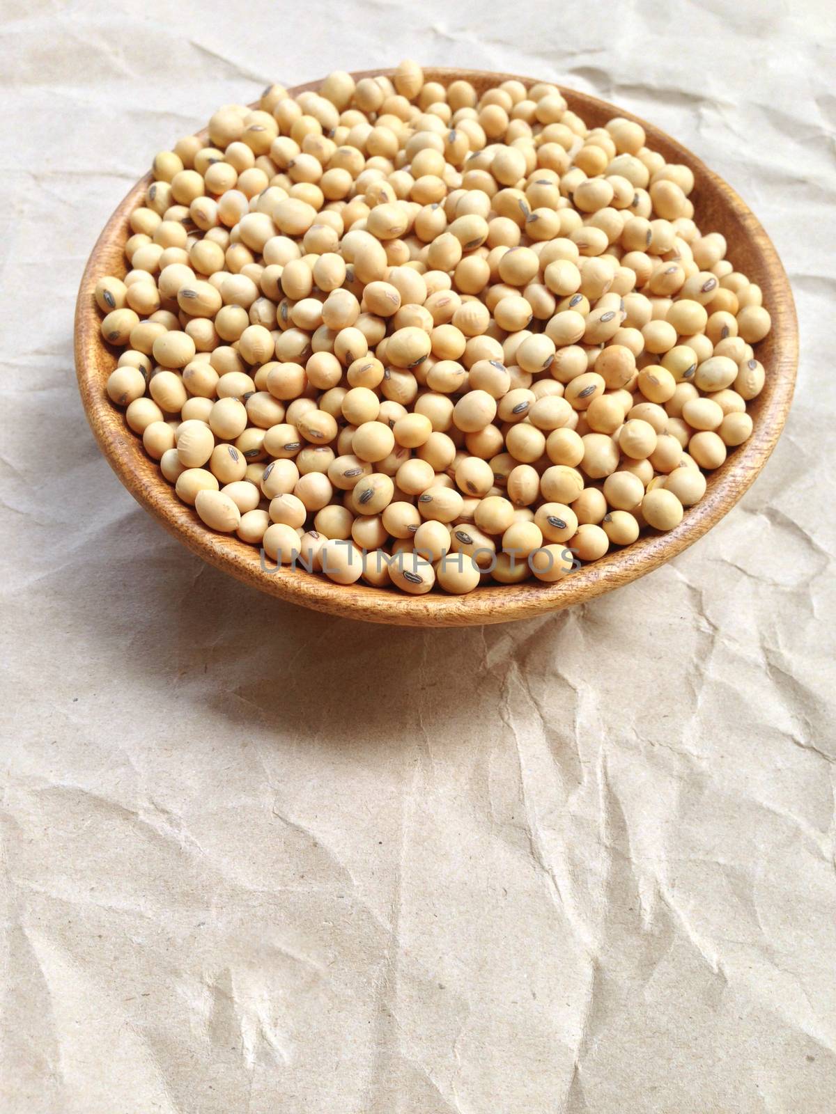 Soy beans in wooden bowl on brown crumpled paper