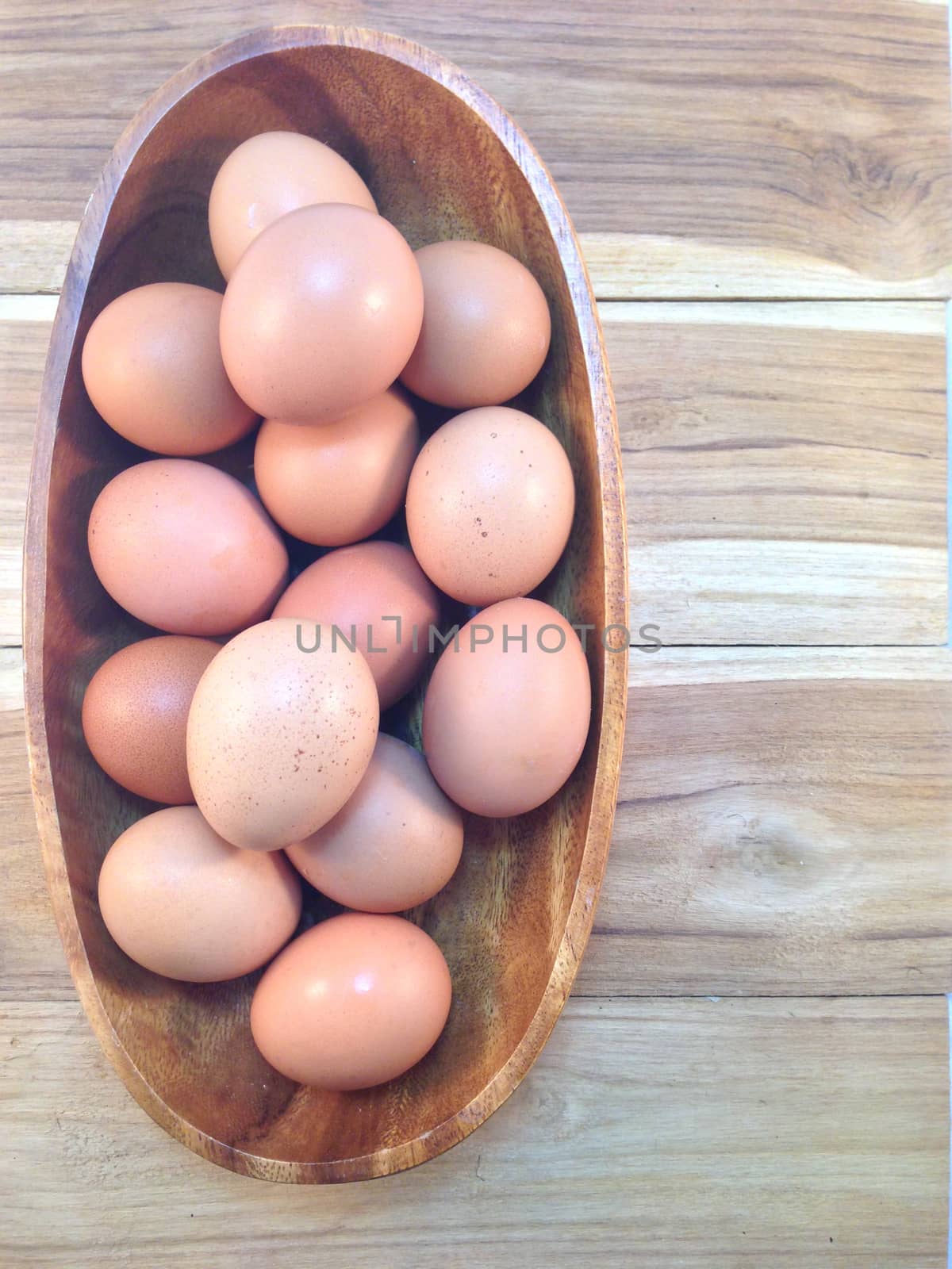 Eggs in wooden bowl on wooden background by Bowonpat