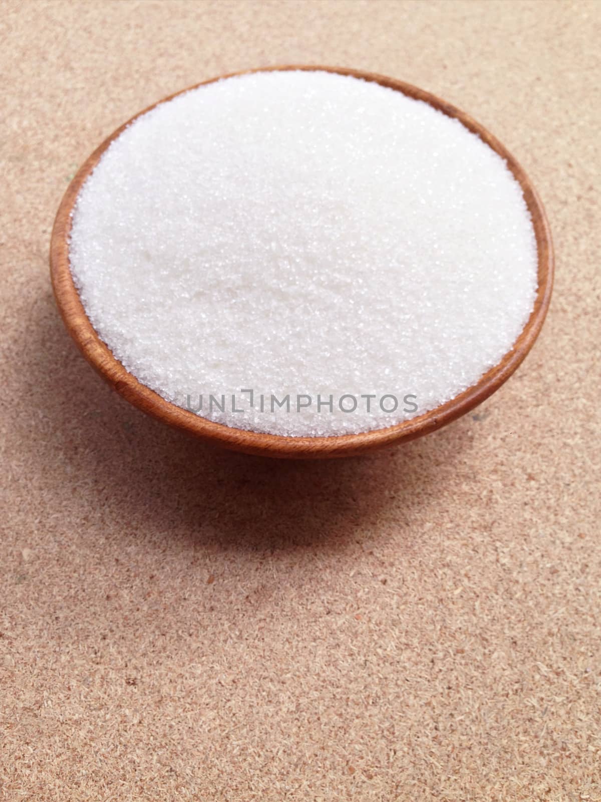 Bowl of sugar on plywood background