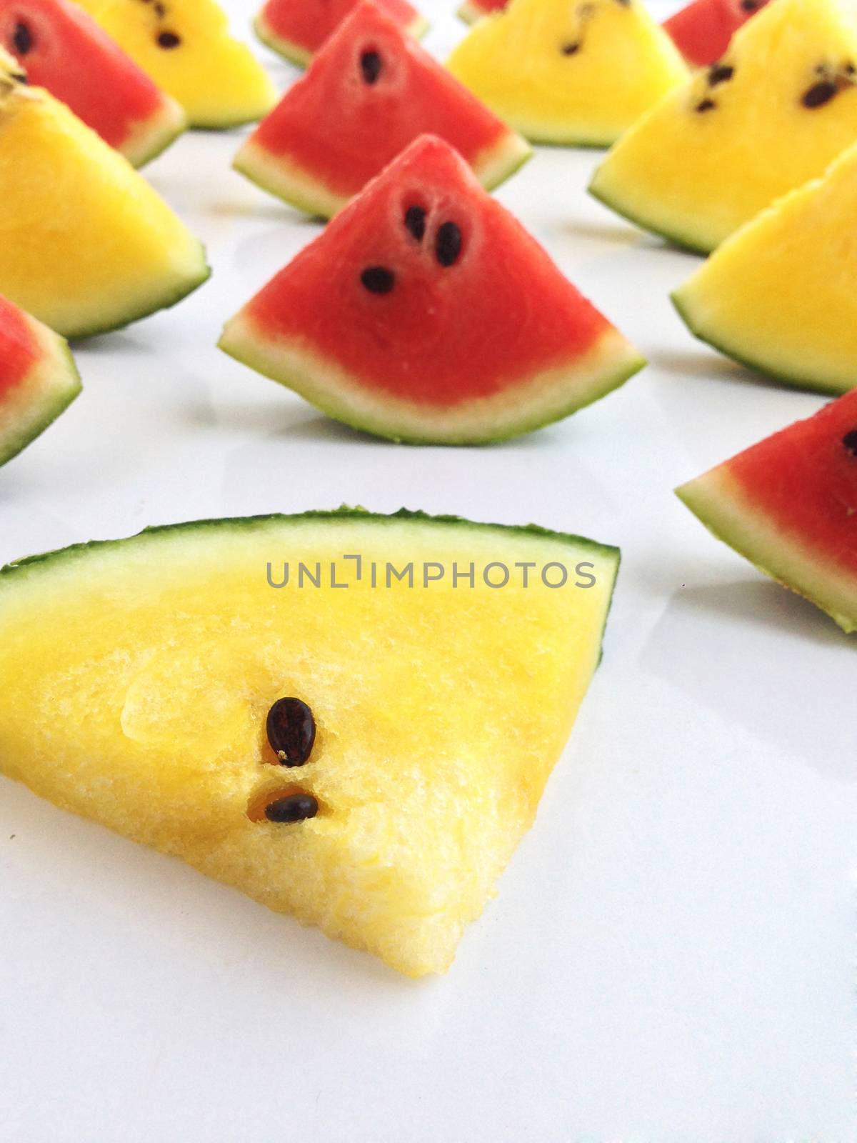 slices of red and yellow watermelon on white background