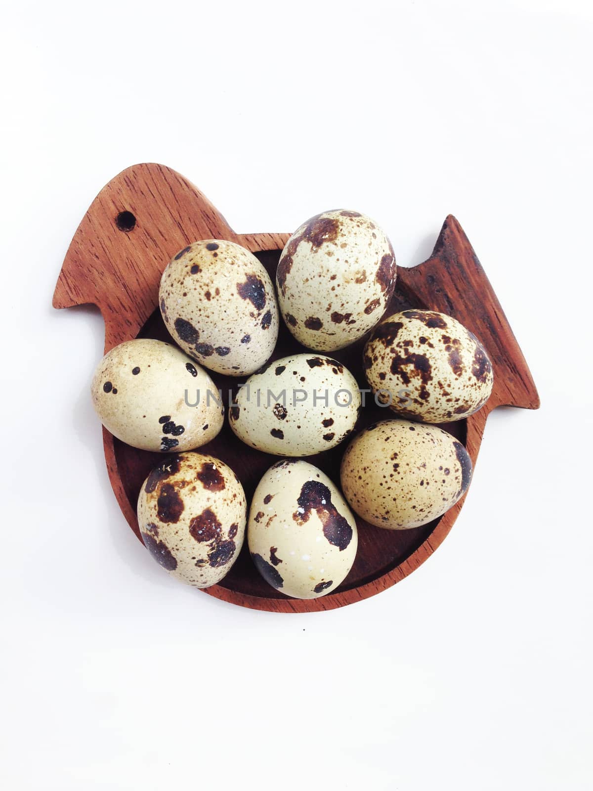 Quail eggs on wooden bird shaped saucer on white background by Bowonpat
