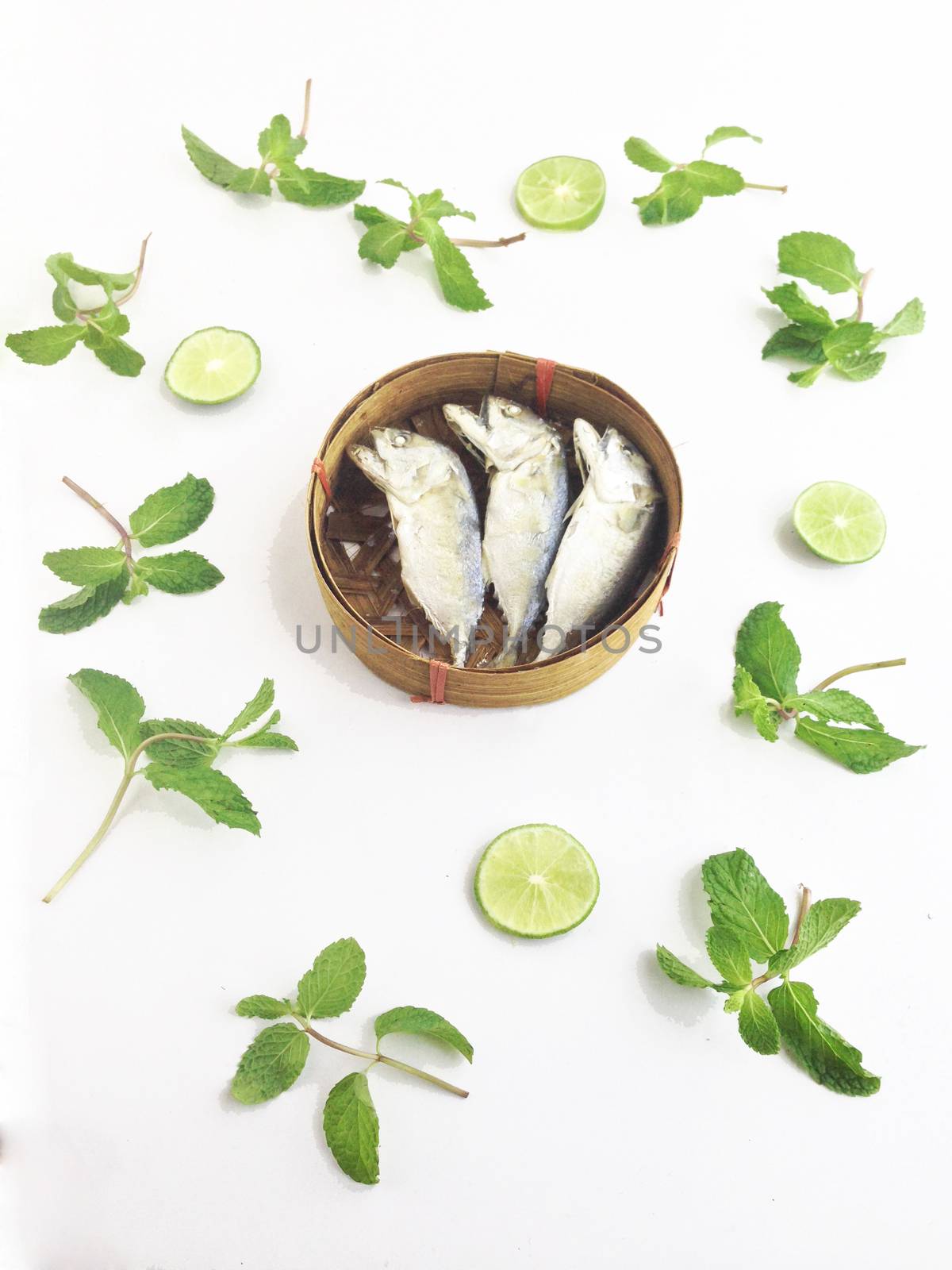 short mackerel on fish basket with paper mint and lime by Bowonpat