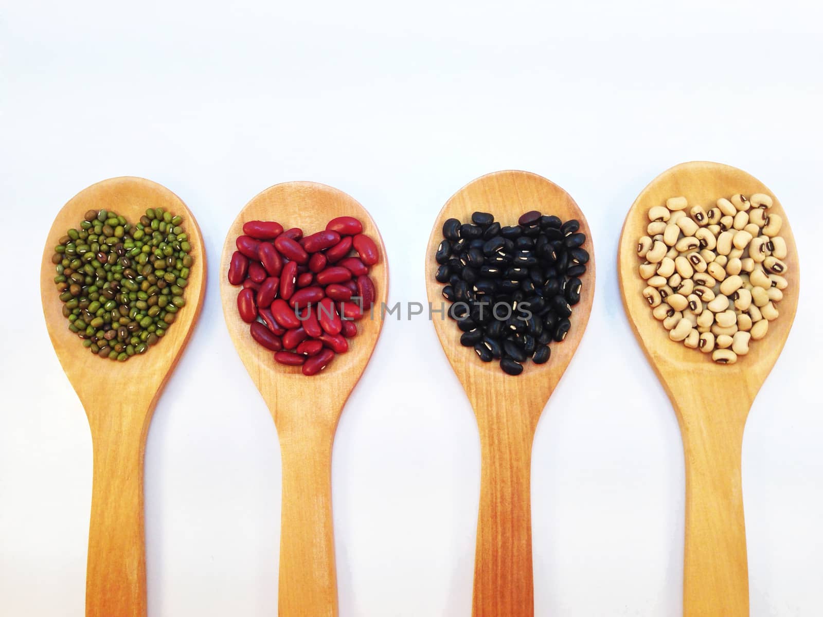 Heart shape, Black eye peas, mung beans, black beans and red kidney beans and wooden ladle on white background