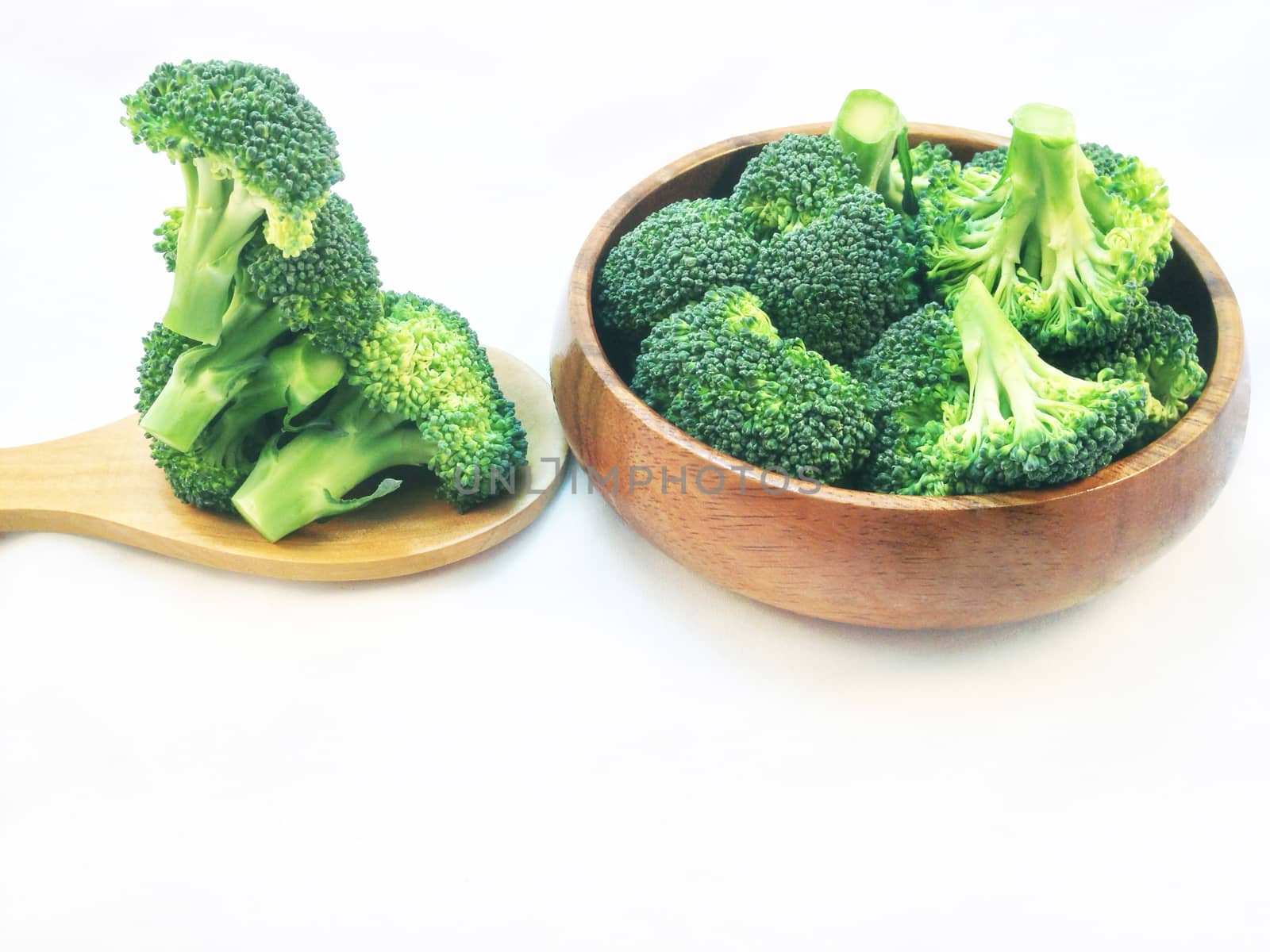 Broccoli in wooden bowl and wooden spoon on white background by Bowonpat