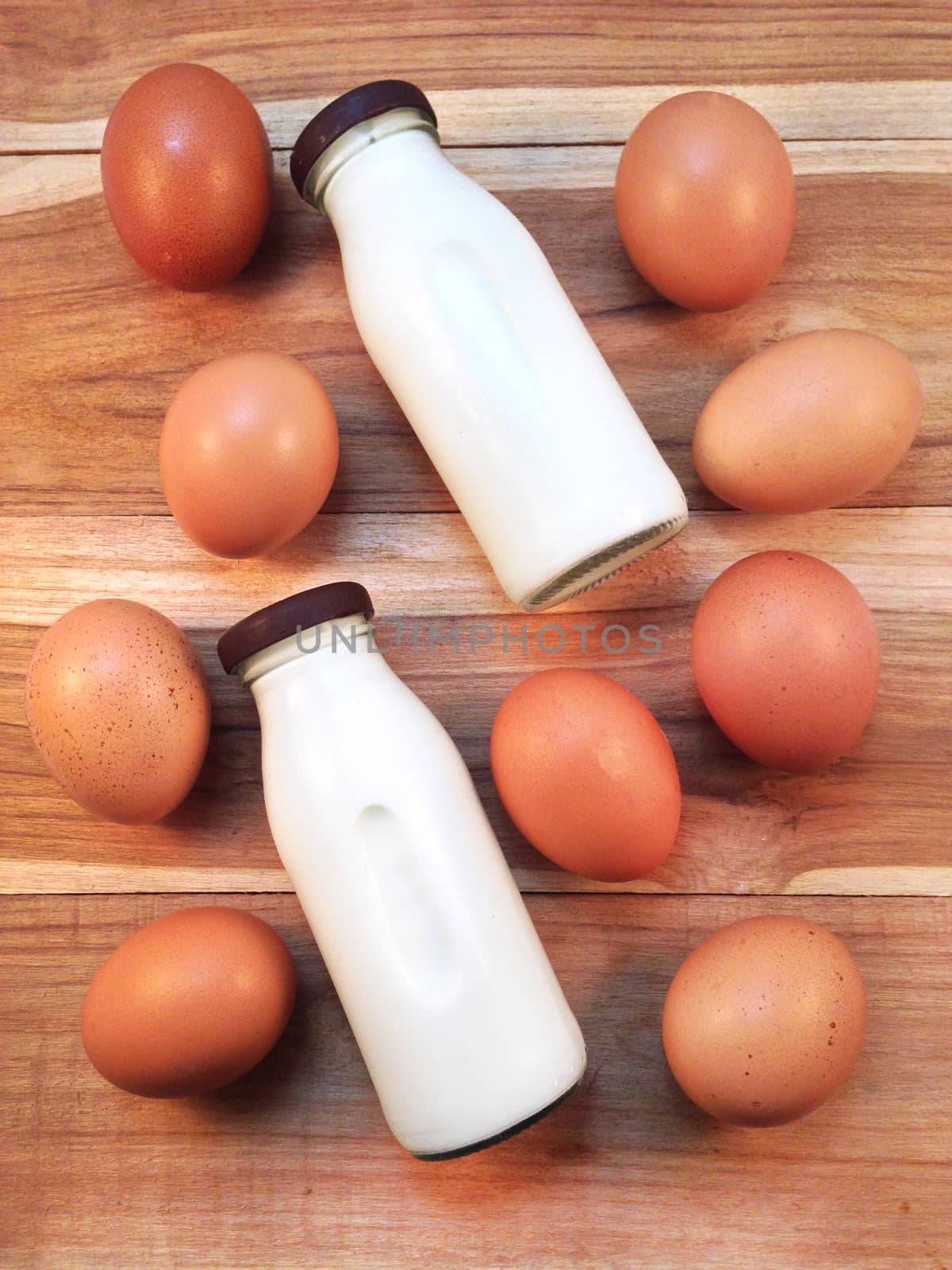 Eggs with bottle of milk on wooden background by Bowonpat