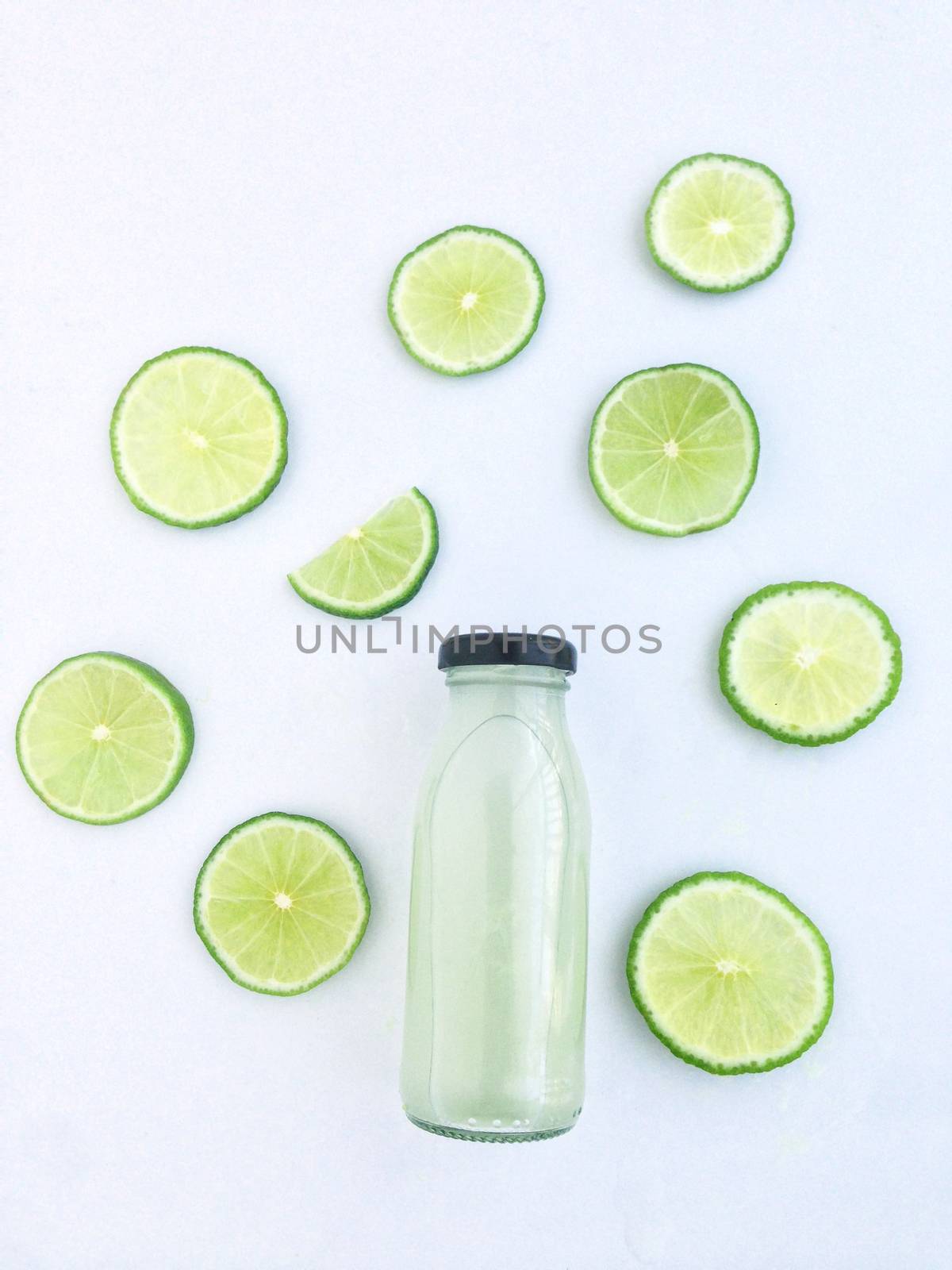 Bottle of lime drinks and Cut into wedges, white background by Bowonpat