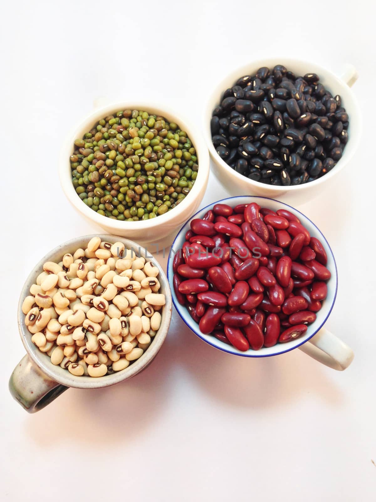Black eye peas, mung beans, black beans and red kidney beans in a cup on white background