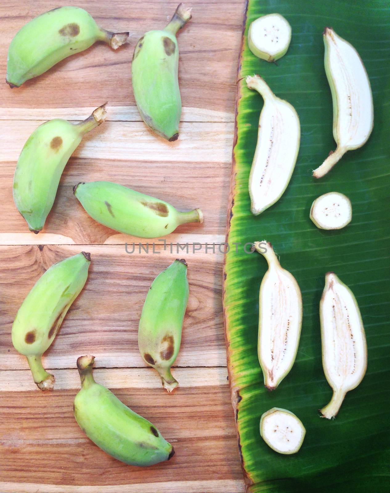 Green cultivated banana and piece of slices on wooden and banana by Bowonpat