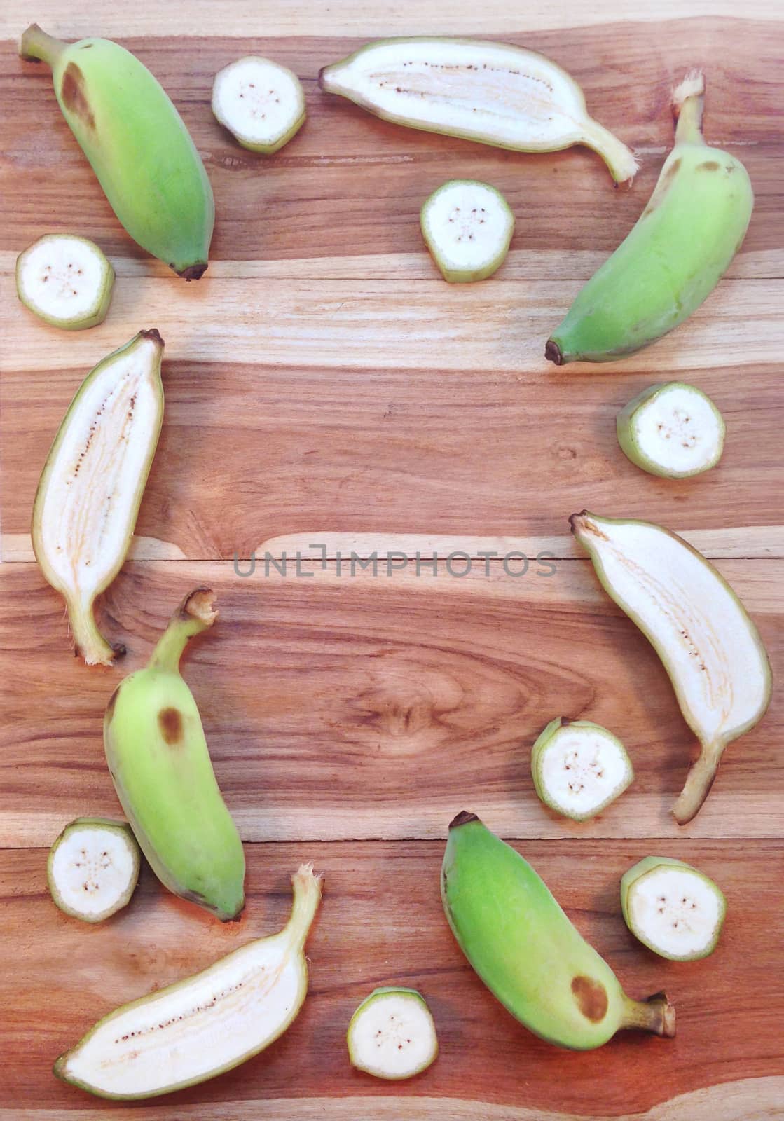 Green cultivated banana and piece of slices on wooden background