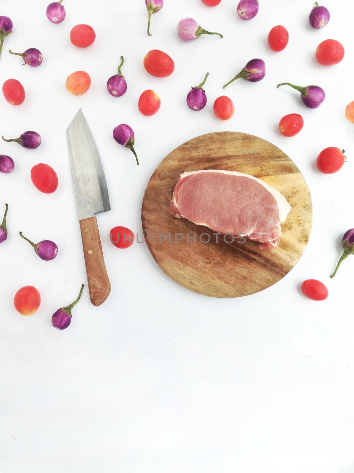 Pork on cutting board with tomatoes and  Thai eggplants