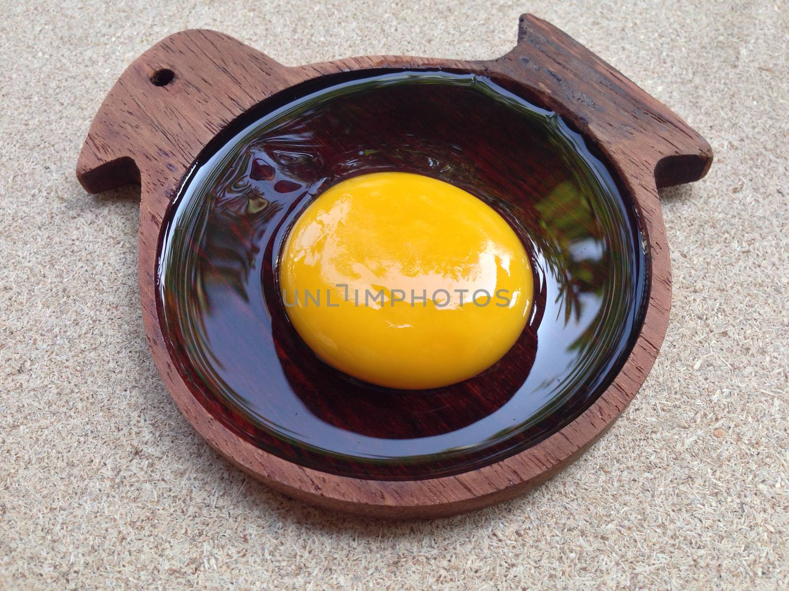 Egg yolk on wooden chicken shaped saucer by Bowonpat