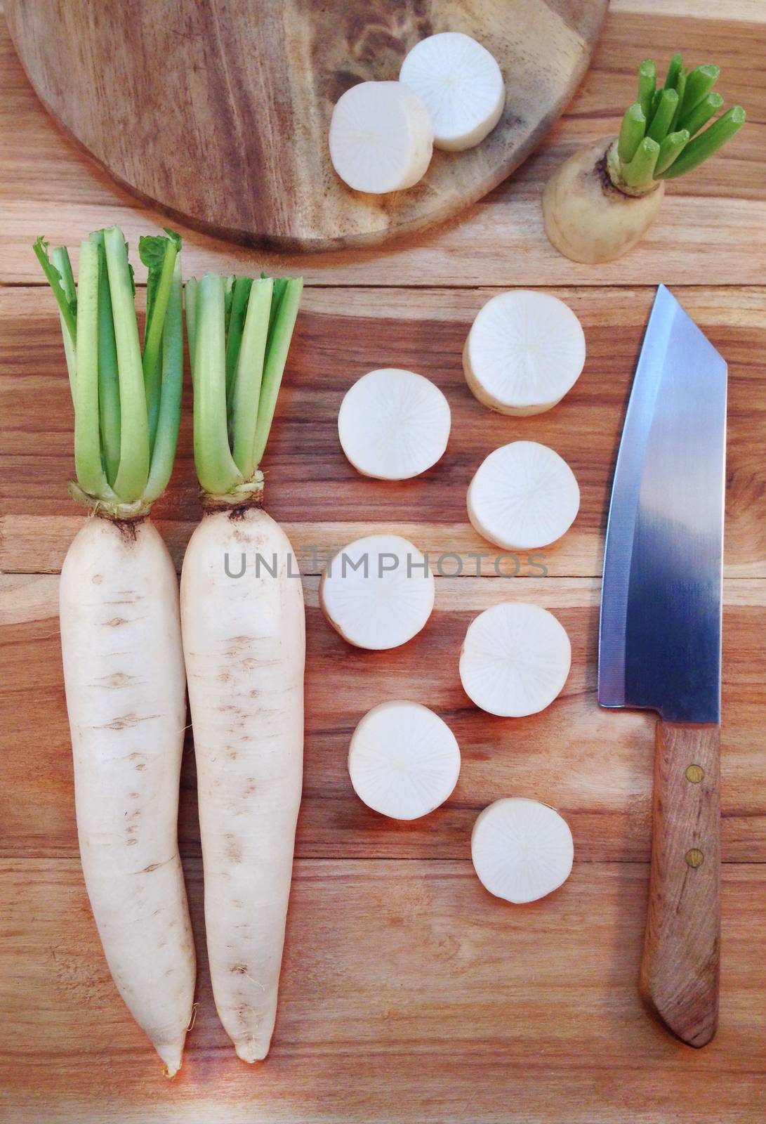 White daikon radish with sliced pieces on wooden table by Bowonpat