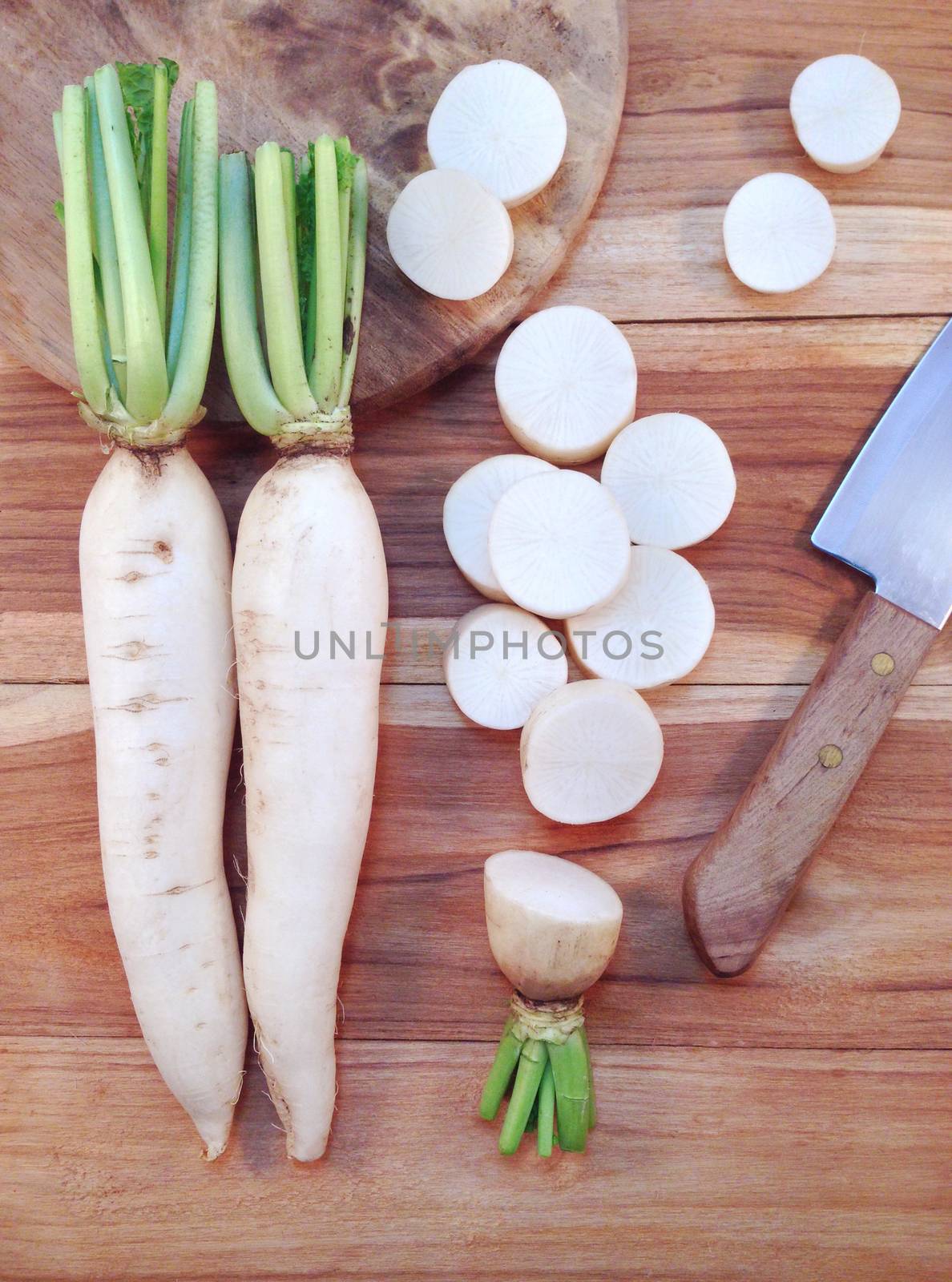 White daikon radish with sliced pieces on wooden table by Bowonpat