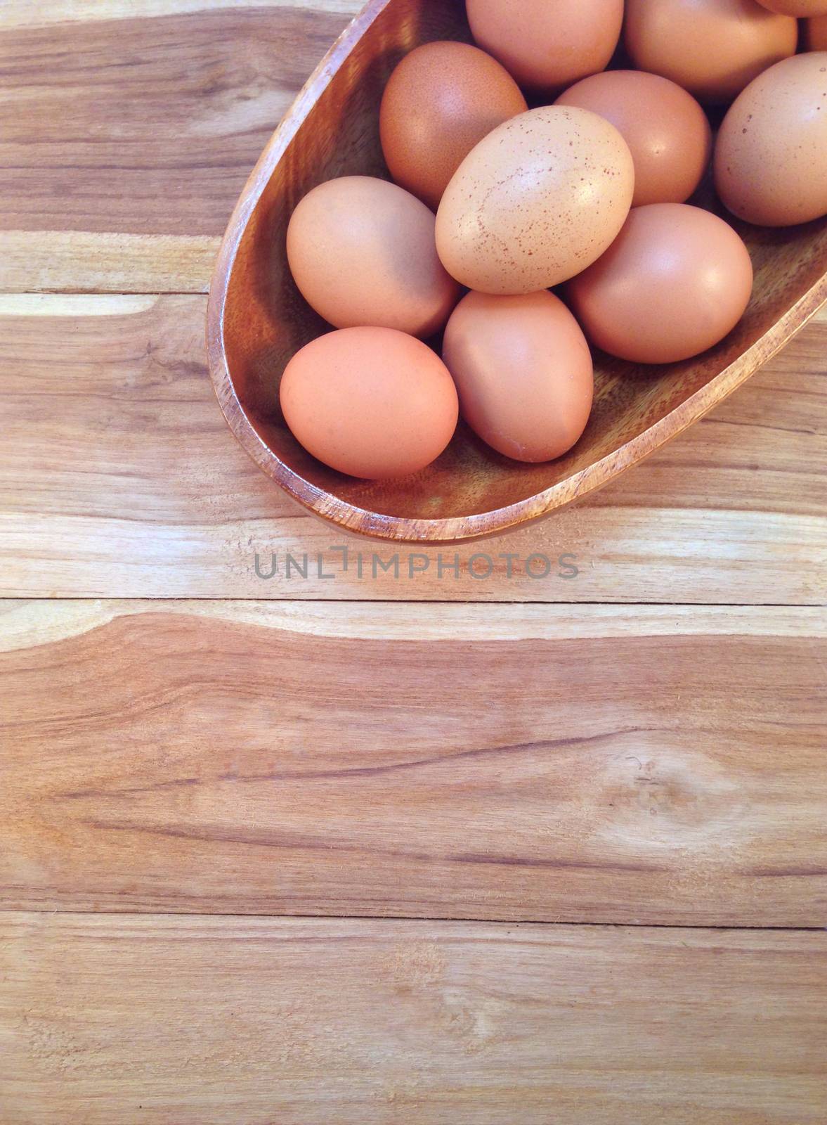 Eggs in wooden bowl on wooden background by Bowonpat