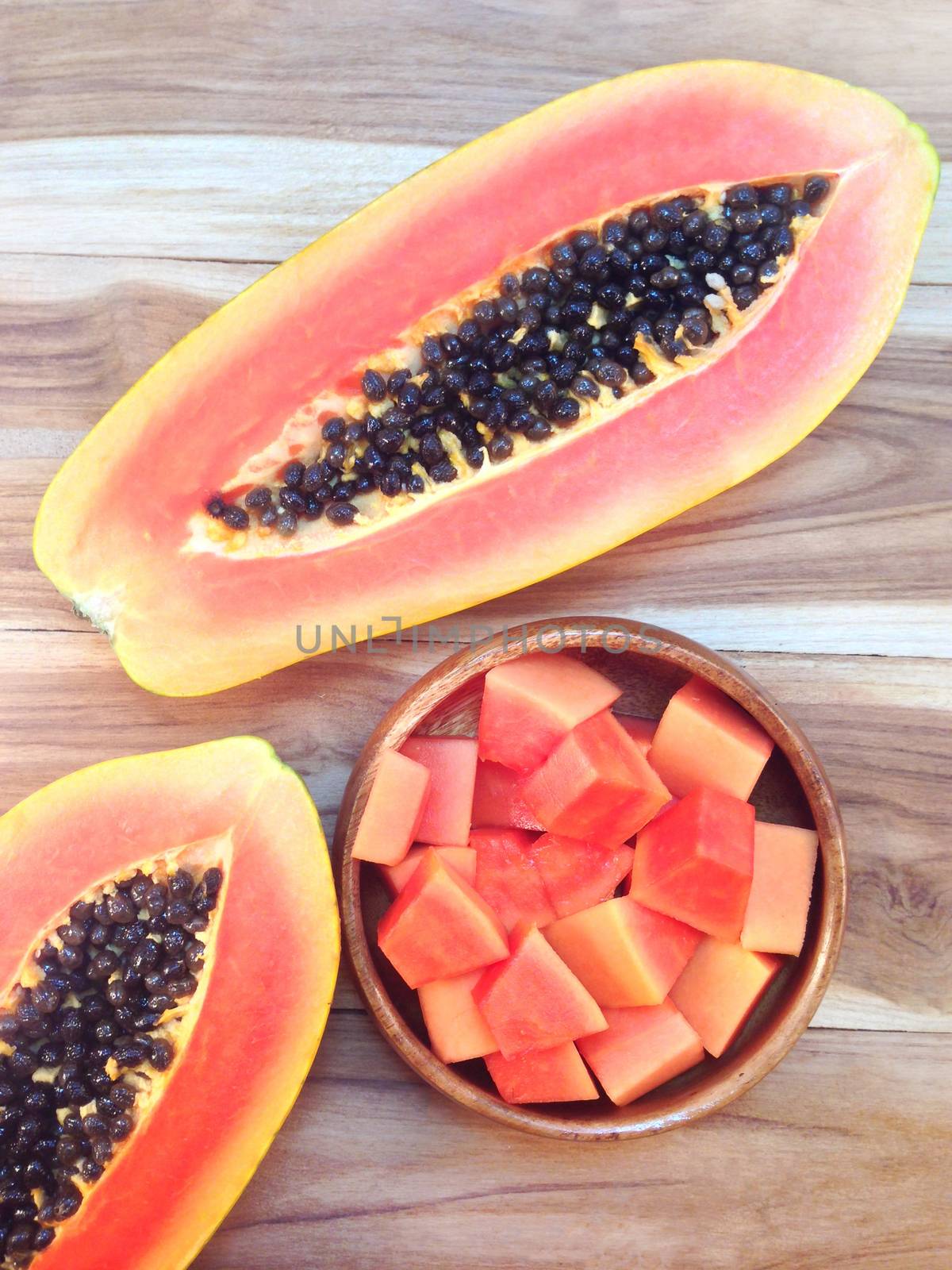 Papaya and sweet papaya slices in wooden bowl on wooden background