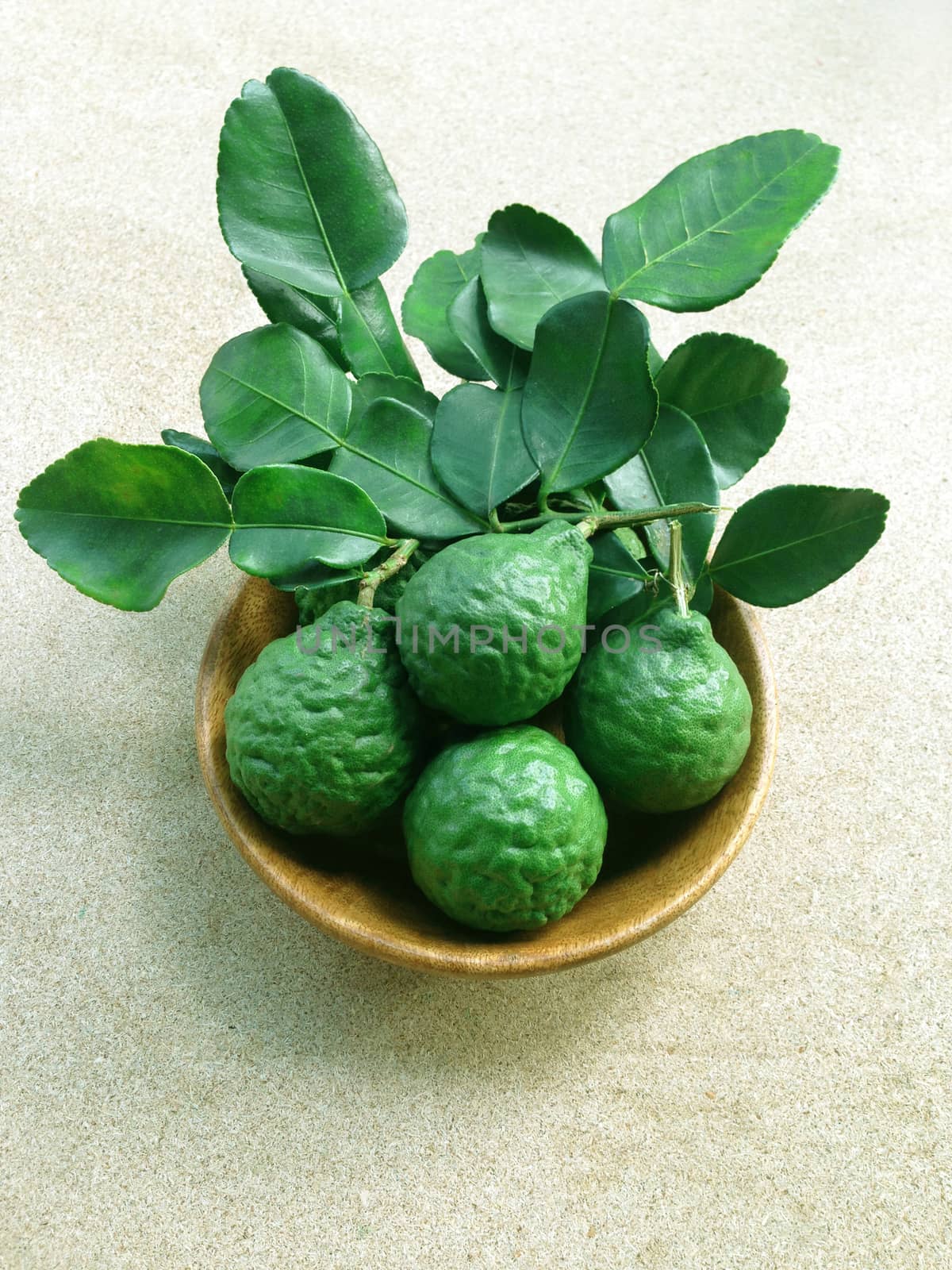 Kaffir Lime or Bergamot in wooden bowl on white background  by Bowonpat