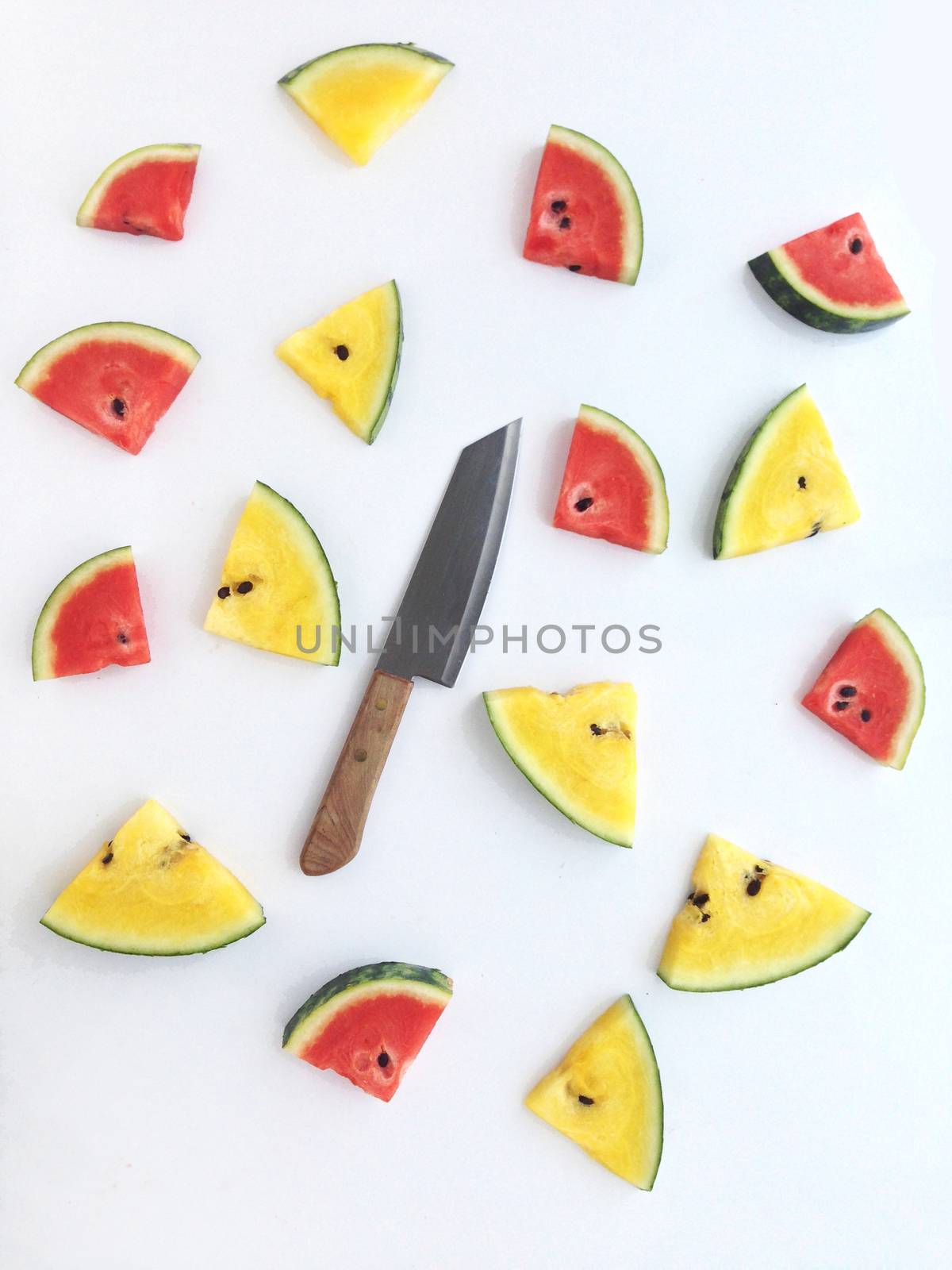 slices of red and yellow watermelon and knife on white background