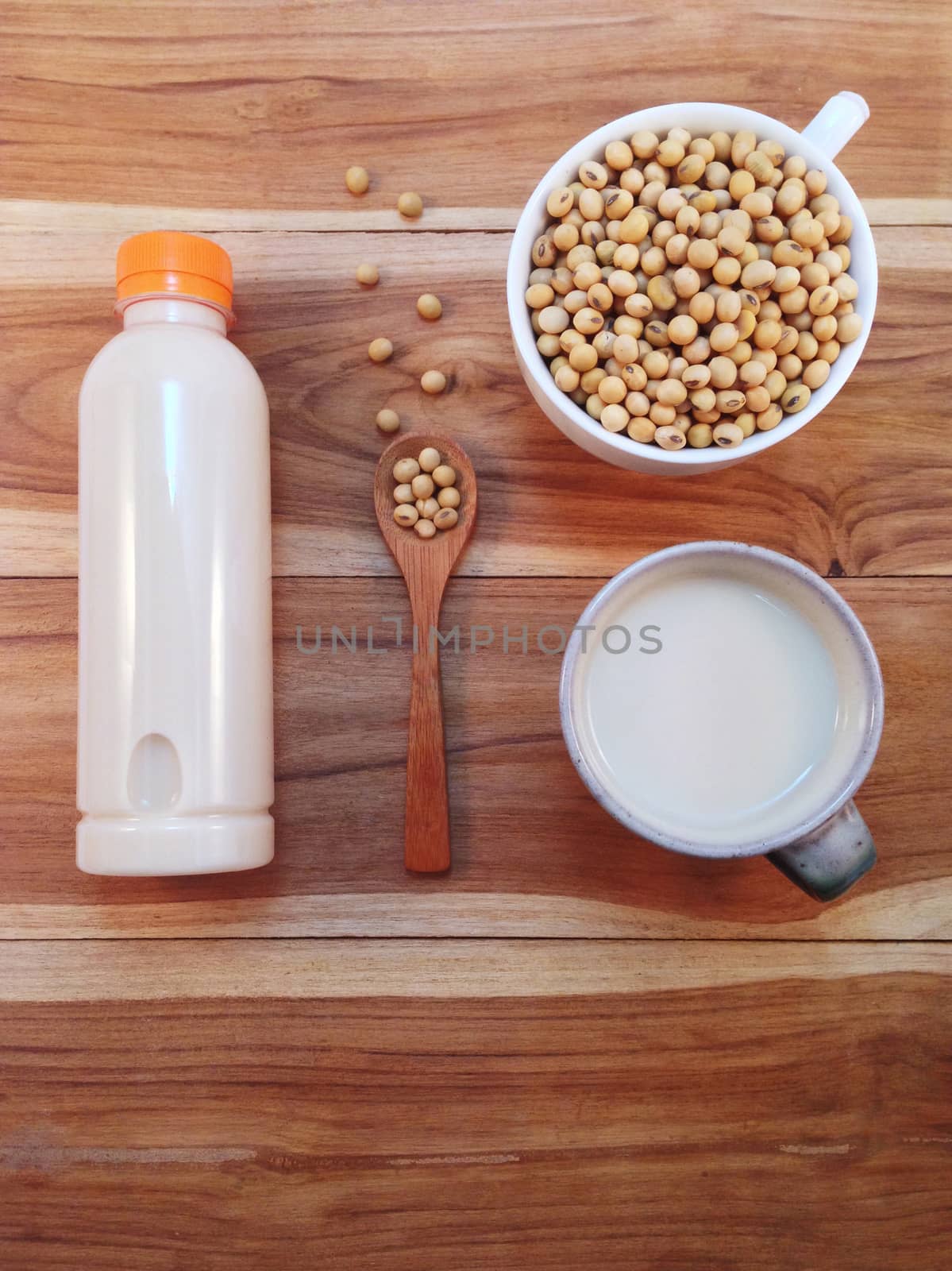 Soy milk in bottle and soy beans with wooden ladle on wooden bac by Bowonpat