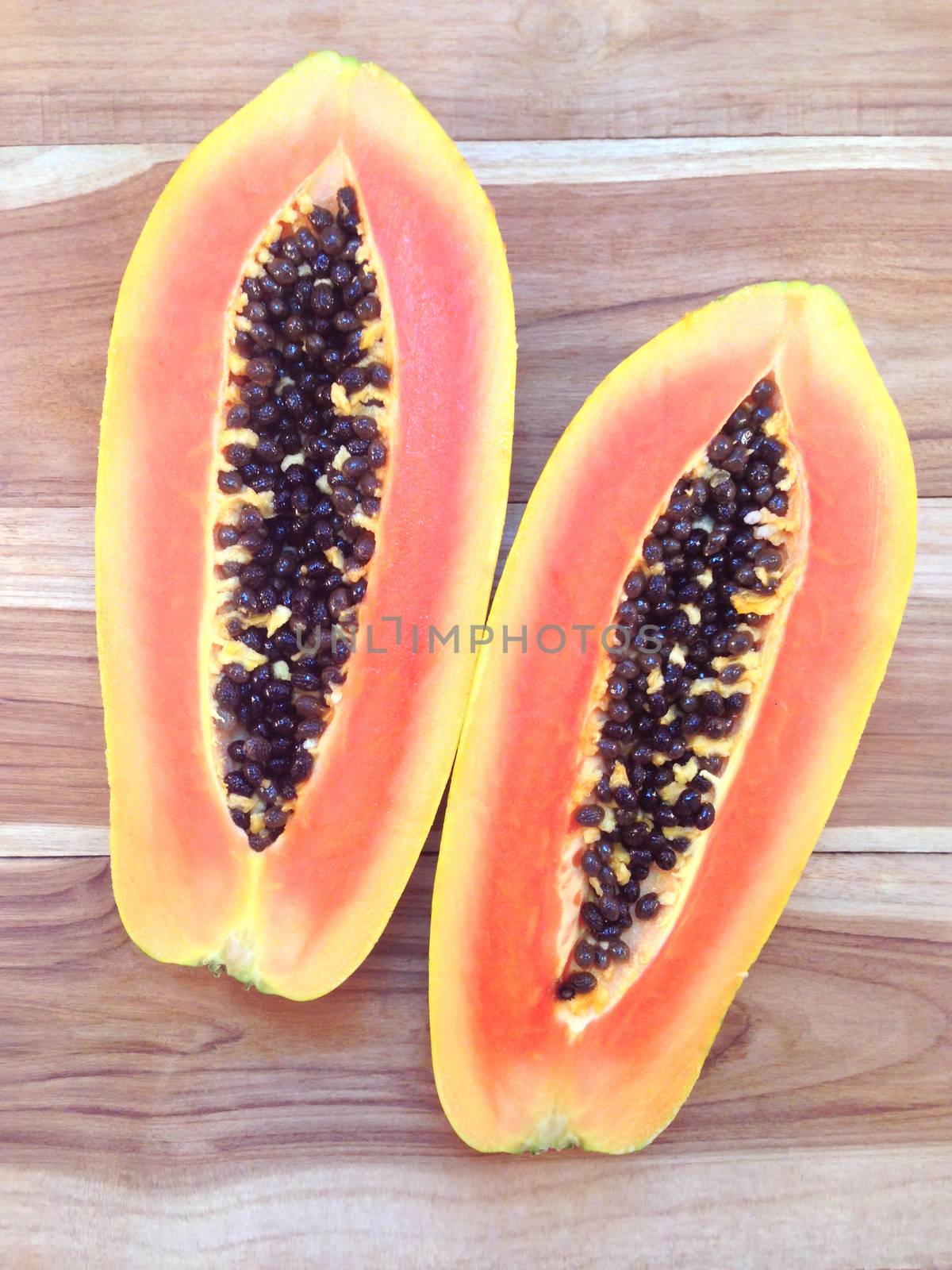 slices of sweet papaya on wooden background by Bowonpat