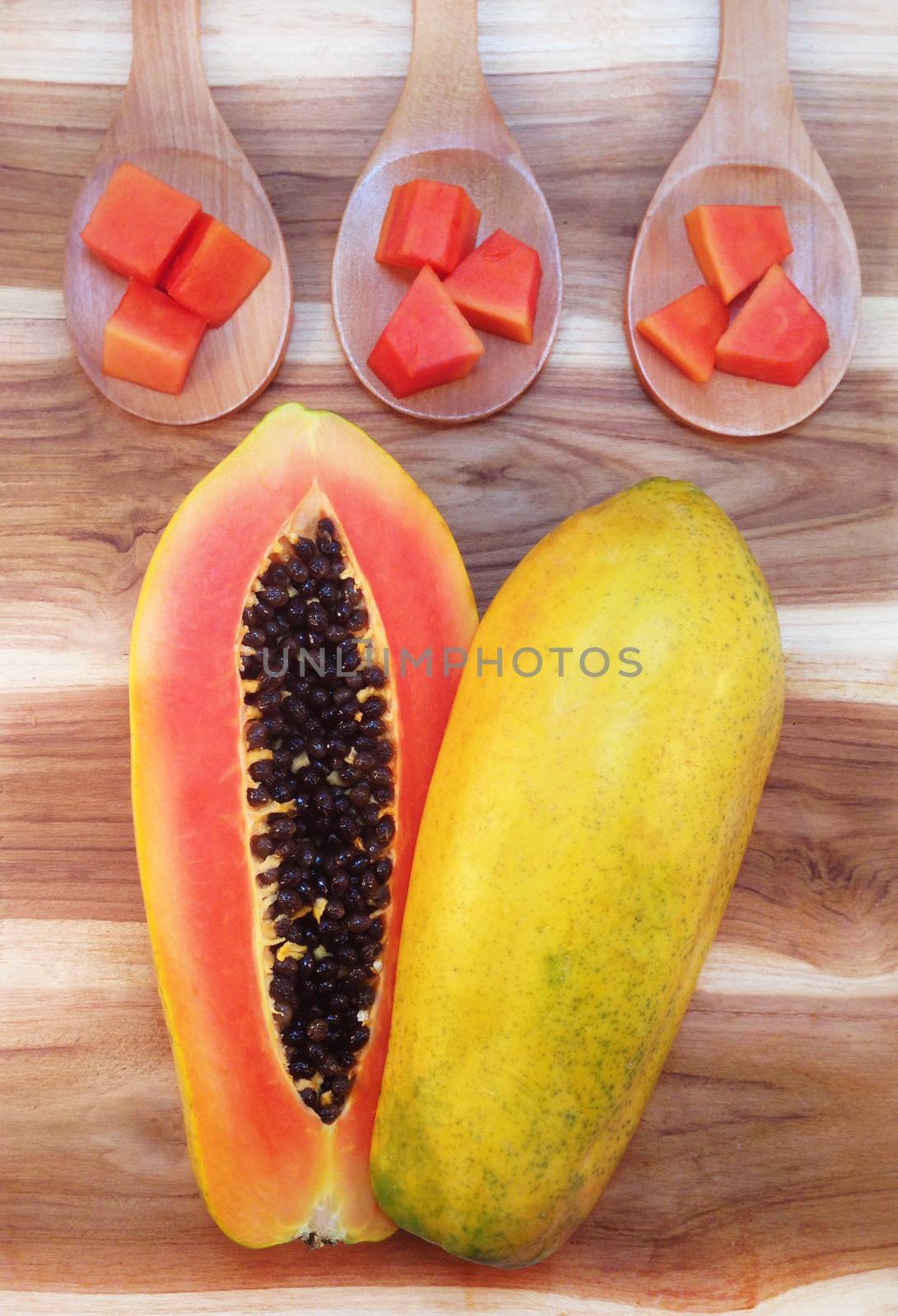 slices of sweet papaya on wooden background by Bowonpat