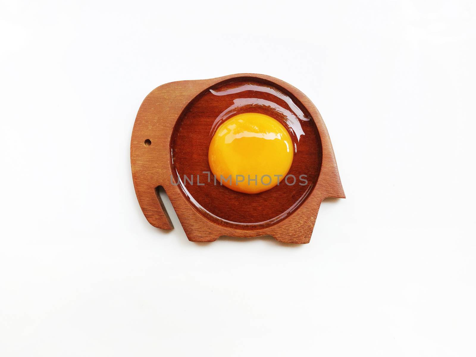 Egg yolk on wooden elephant shaped saucer on white background
