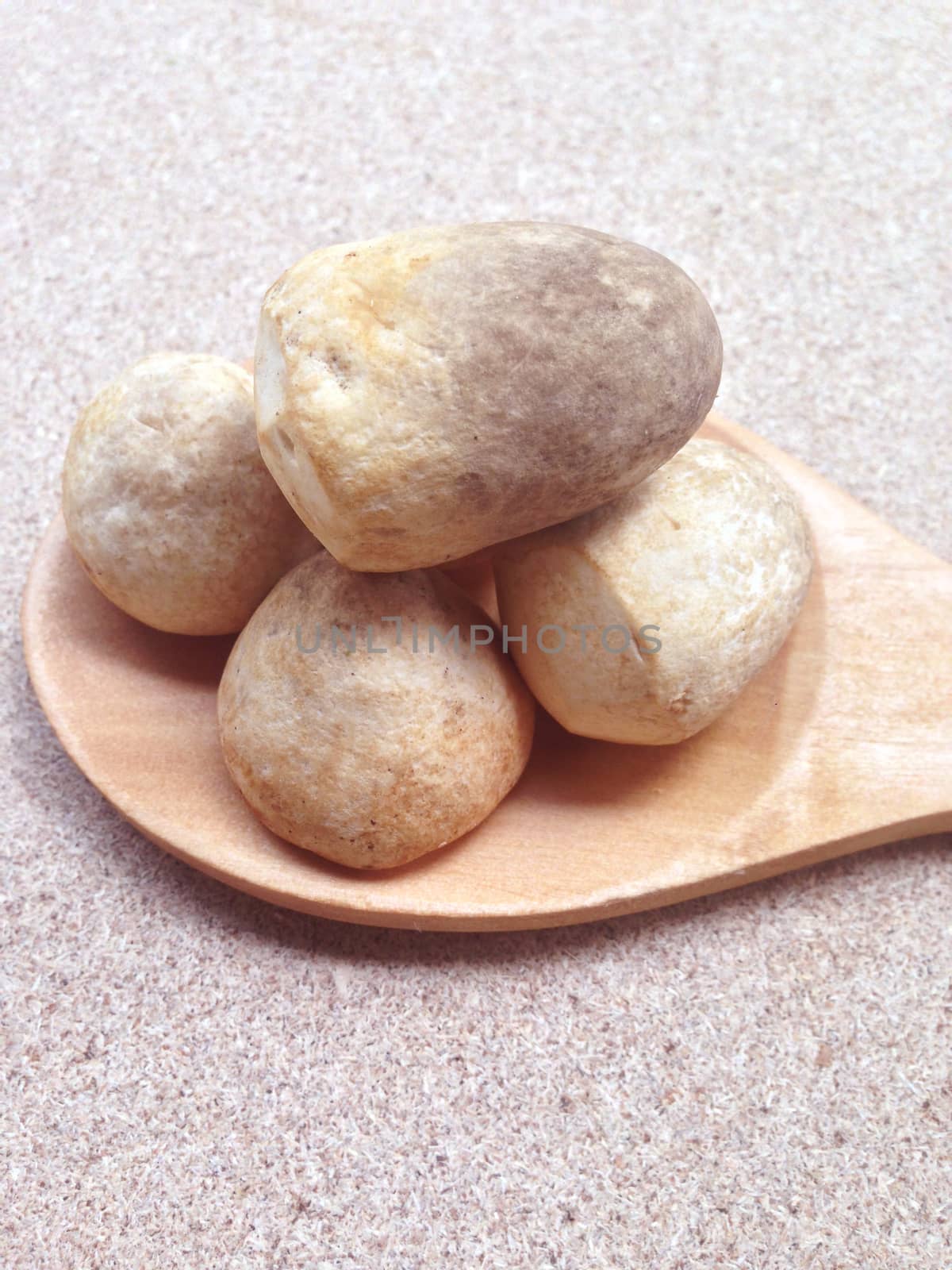 Straw mushroom with wooden spoon on plywood background