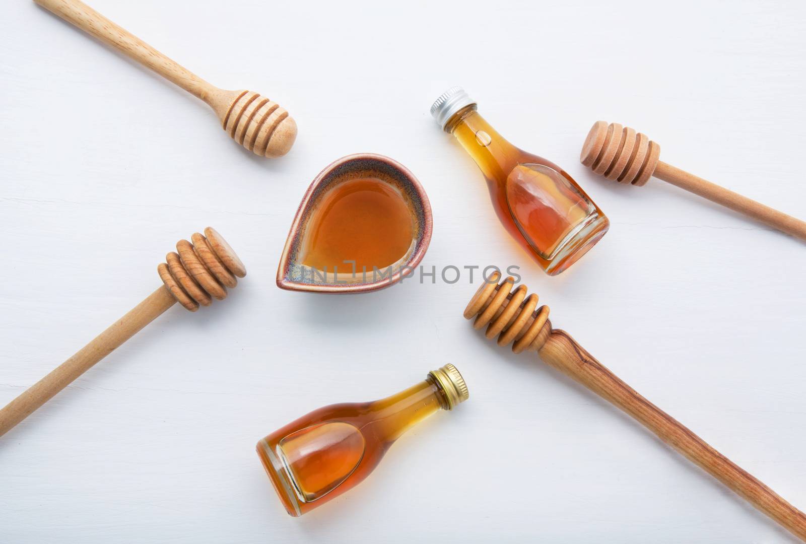 Honey with wooden dipper and little honey bottle on white wooden by Bowonpat