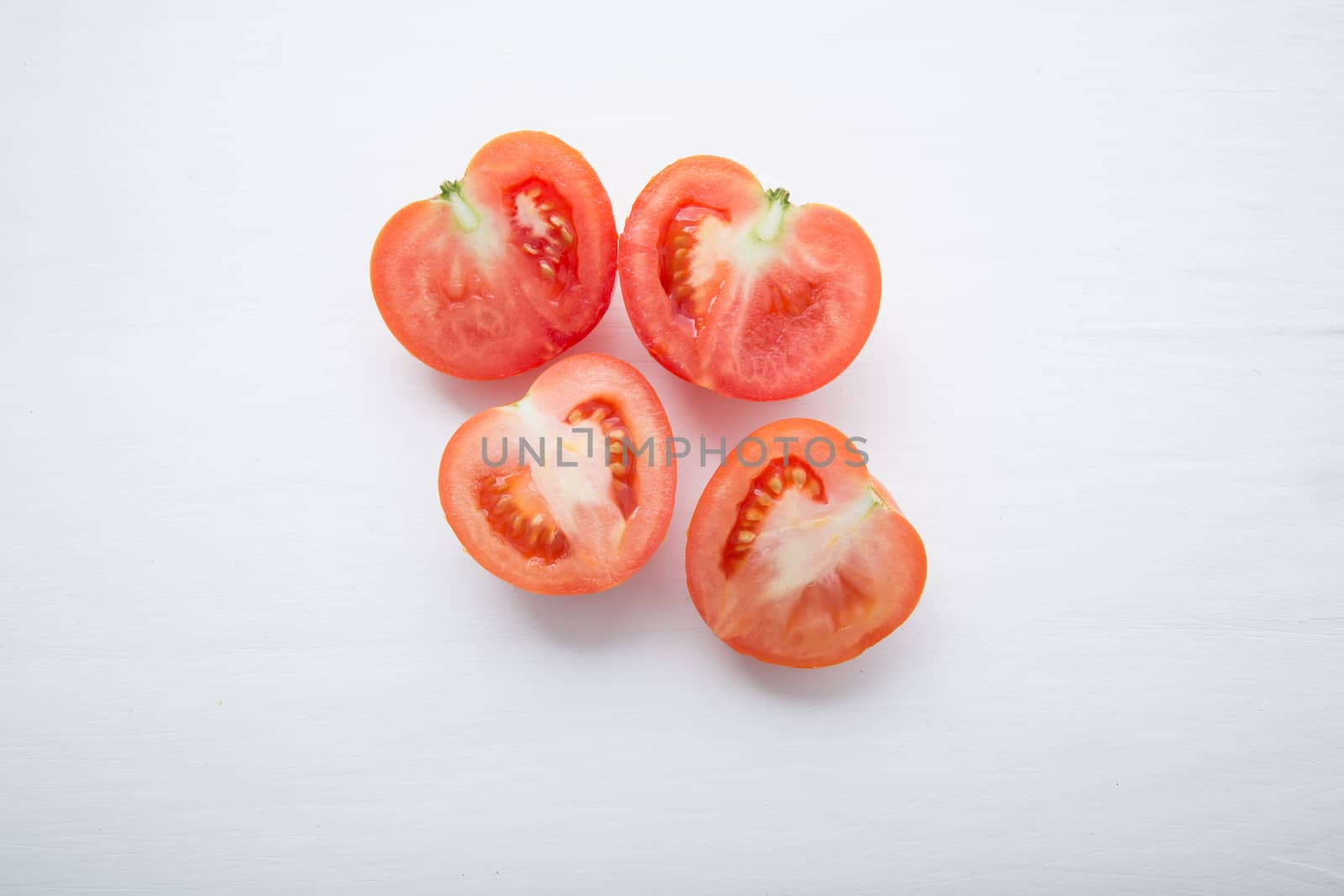 Fresh tomatoes slices on white wooden background.