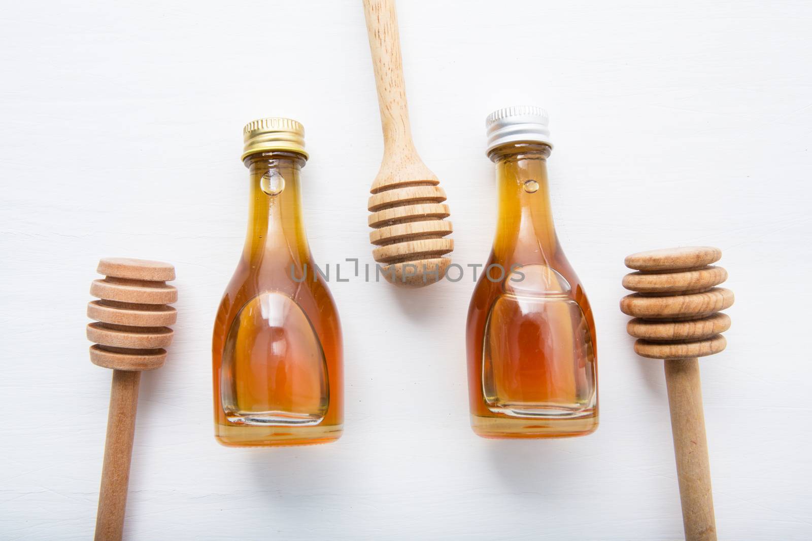 wooden dipper and little honey bottle on white wooden background.