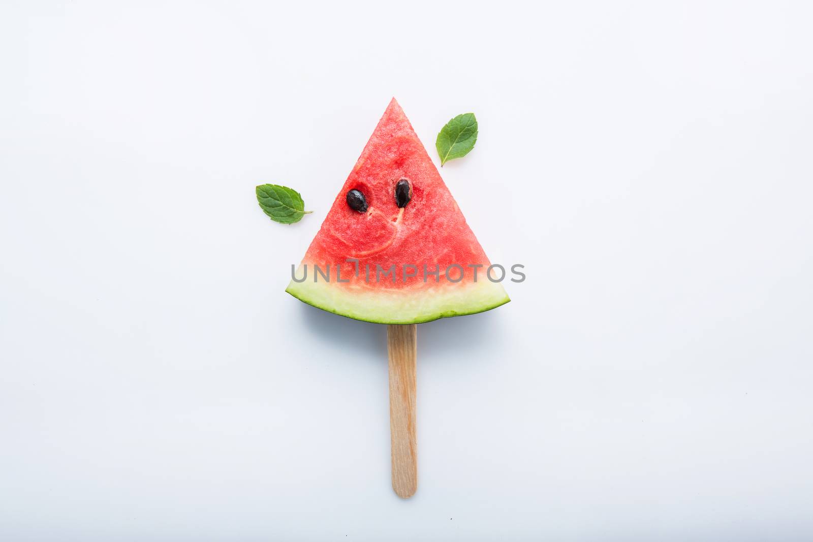 Watermelon slice popsicles and paper mint on white wooden background.