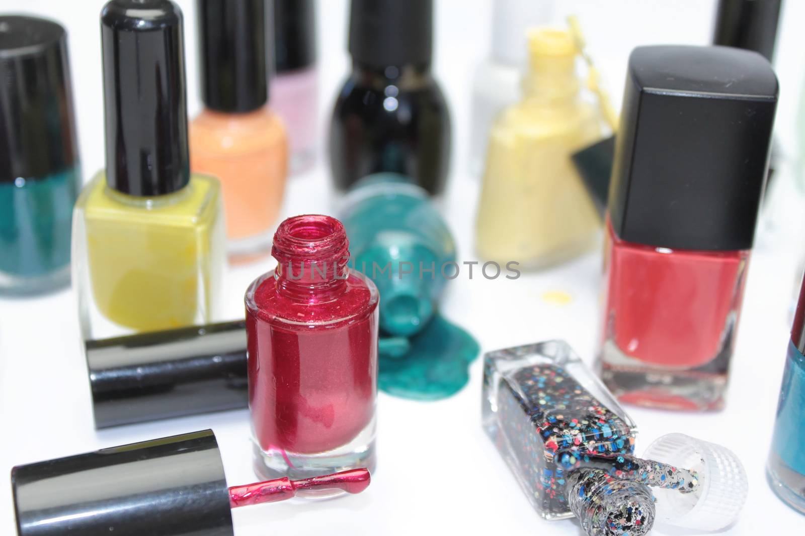 Nail polish assortment of bright colors on white background with colorful drops by Kasia_Lawrynowicz