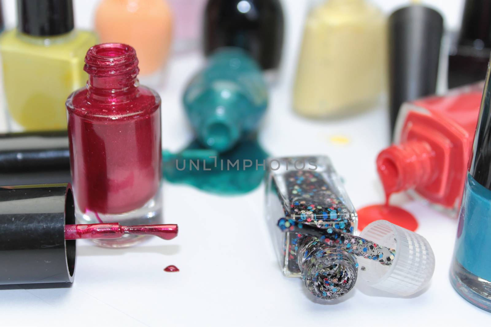 Nail polish assortment of bright colors on white background with colorful drops by Kasia_Lawrynowicz