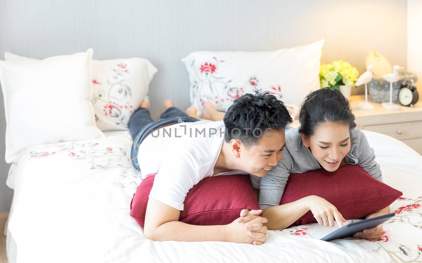 Couples lying using tablet on bed by vichie81