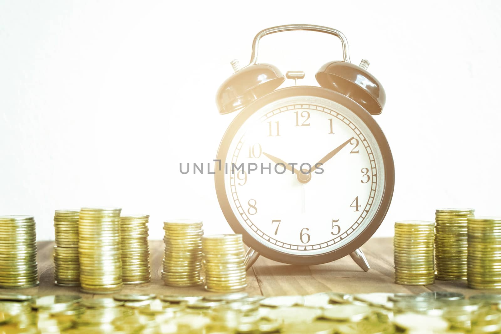 Stack Of Gold Coins With Black Fashioned Alarm Clock For Display by rakoptonLPN