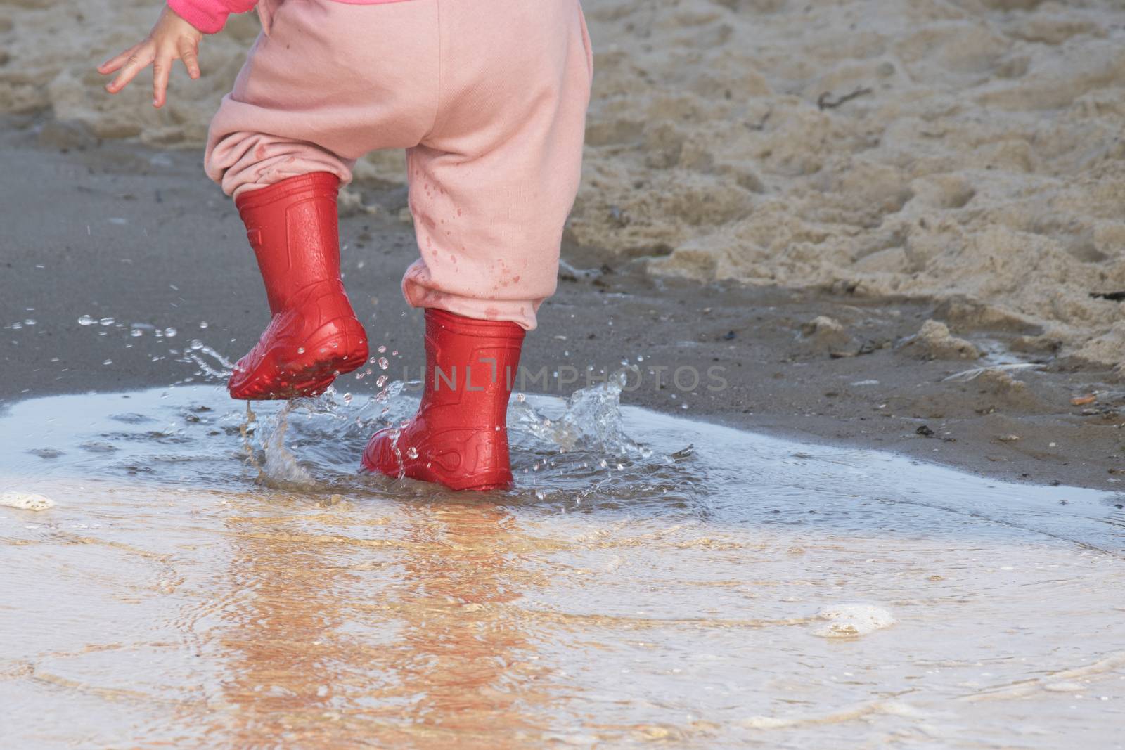 wellingtons in puddle.kid rubber boots in the sea background