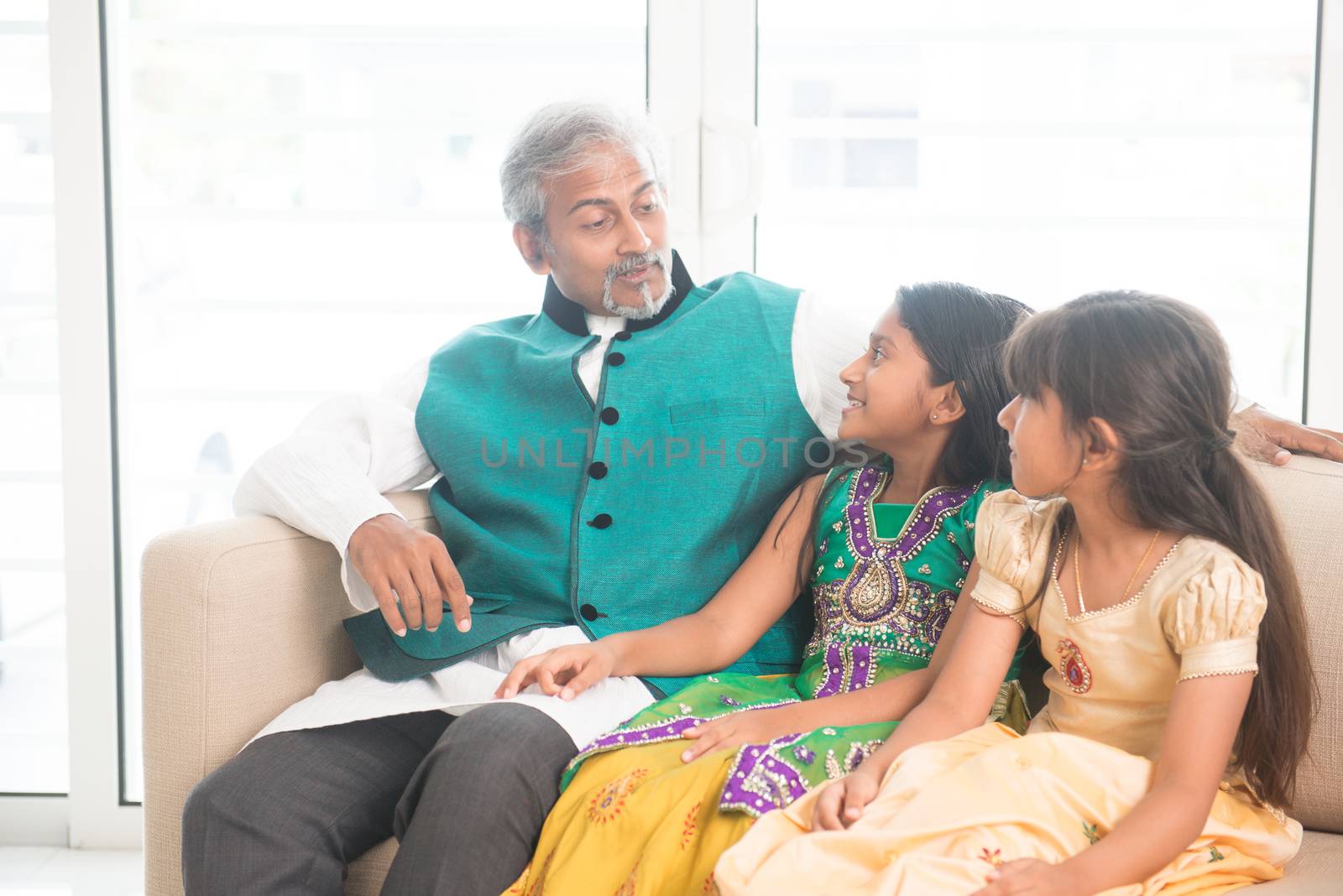 Portrait of Indian family talking at home. Happy Asian father and children indoors lifestyle.
