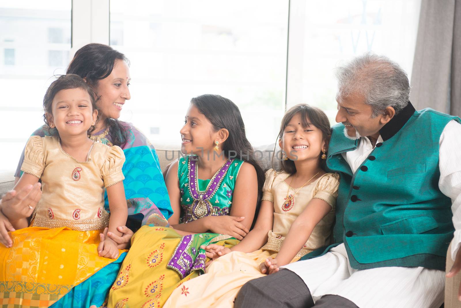 Portrait of happy Indian family talking at home. Asian parents and children indoors lifestyle.