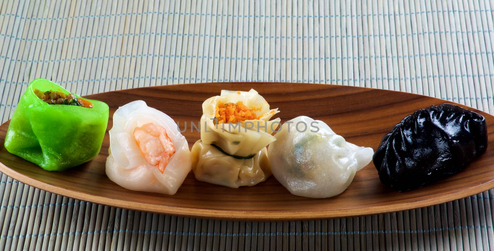 Various Dim Sum In a Row on Bamboo Plate closeup on Straw Mat background