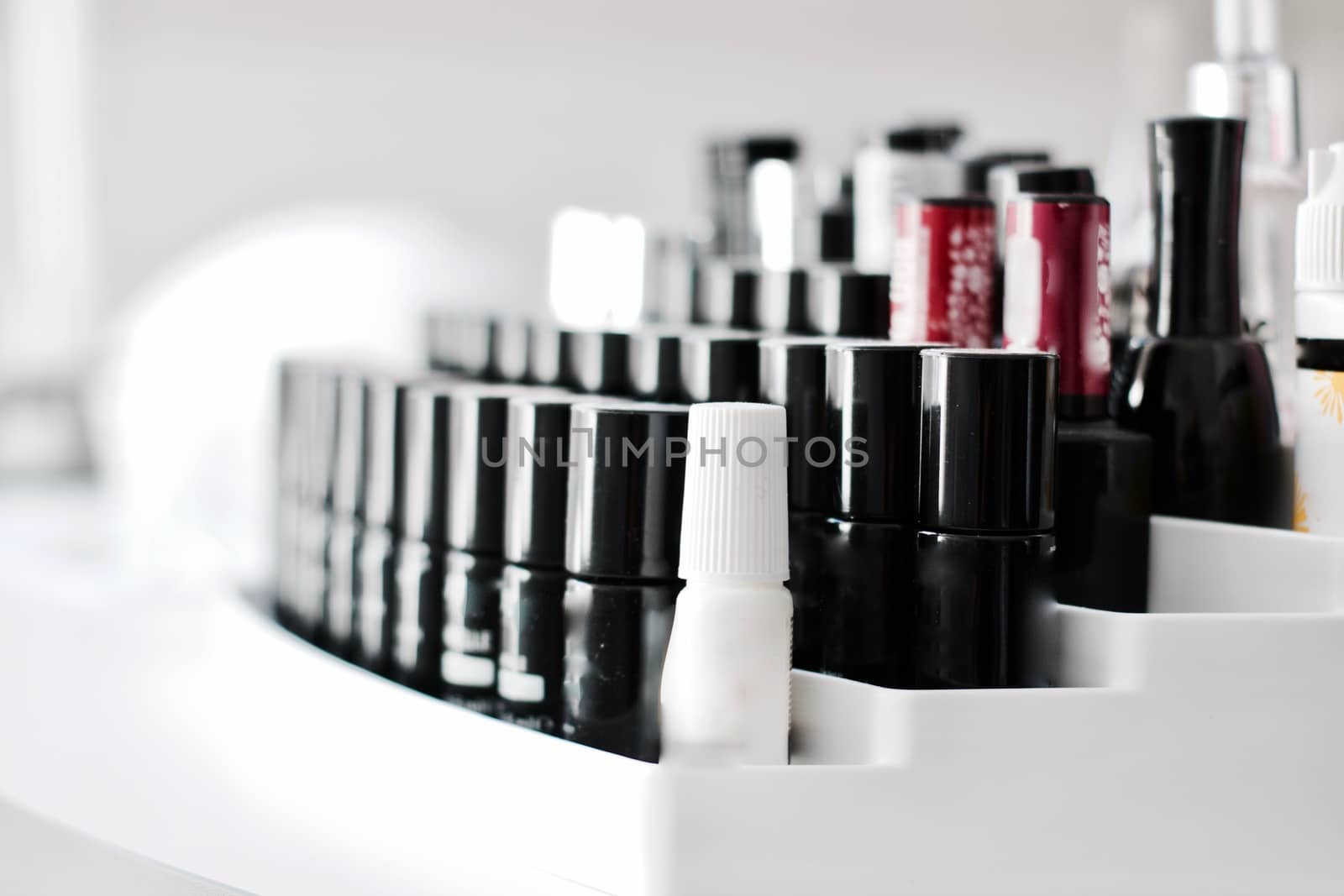 Black small bottles with nails lacquer on the white holder in SPA salon.