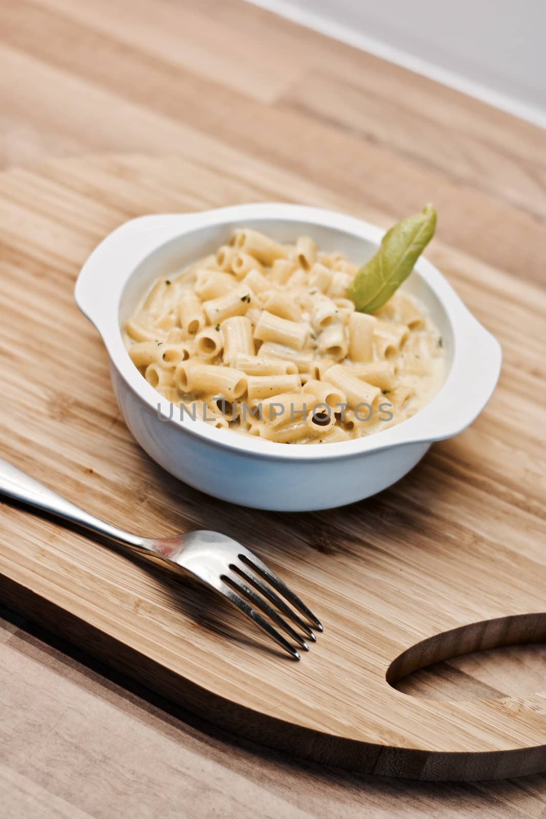 Delicious and fresh pasta on white plate on wooden board in the kitchen. Cooking concept.