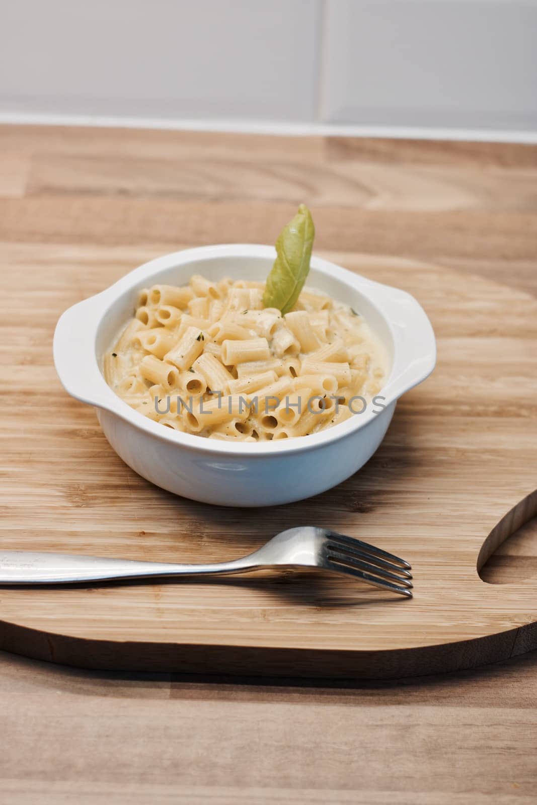 Delicious and fresh pasta on white plate on wooden board in the kitchen. Cooking concept.
