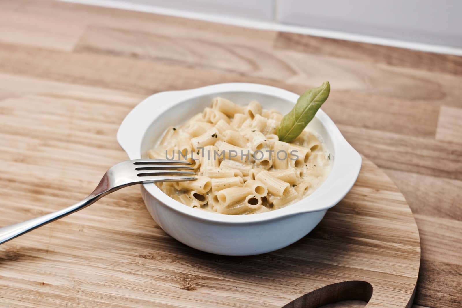 Delicious and fresh pasta on white plate on wooden board in the kitchen. Cooking concept.
