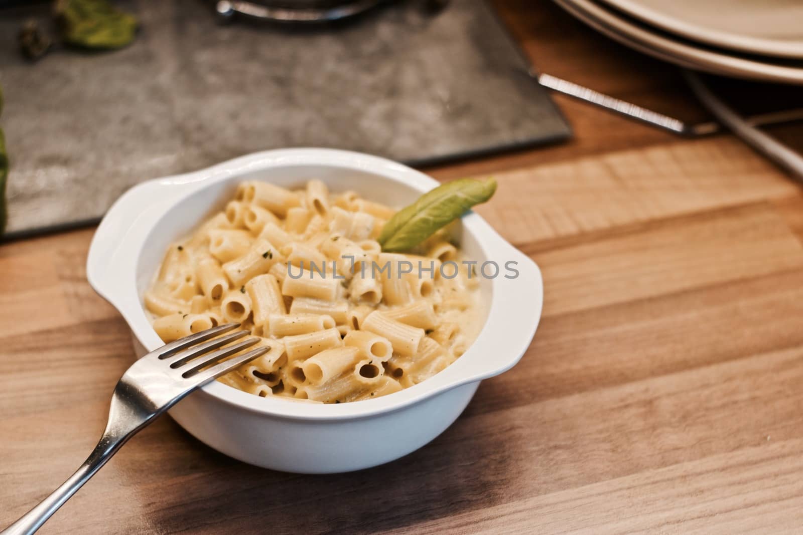Delicious and fresh pasta on white plate on wooden board in the kitchen. Cooking concept.