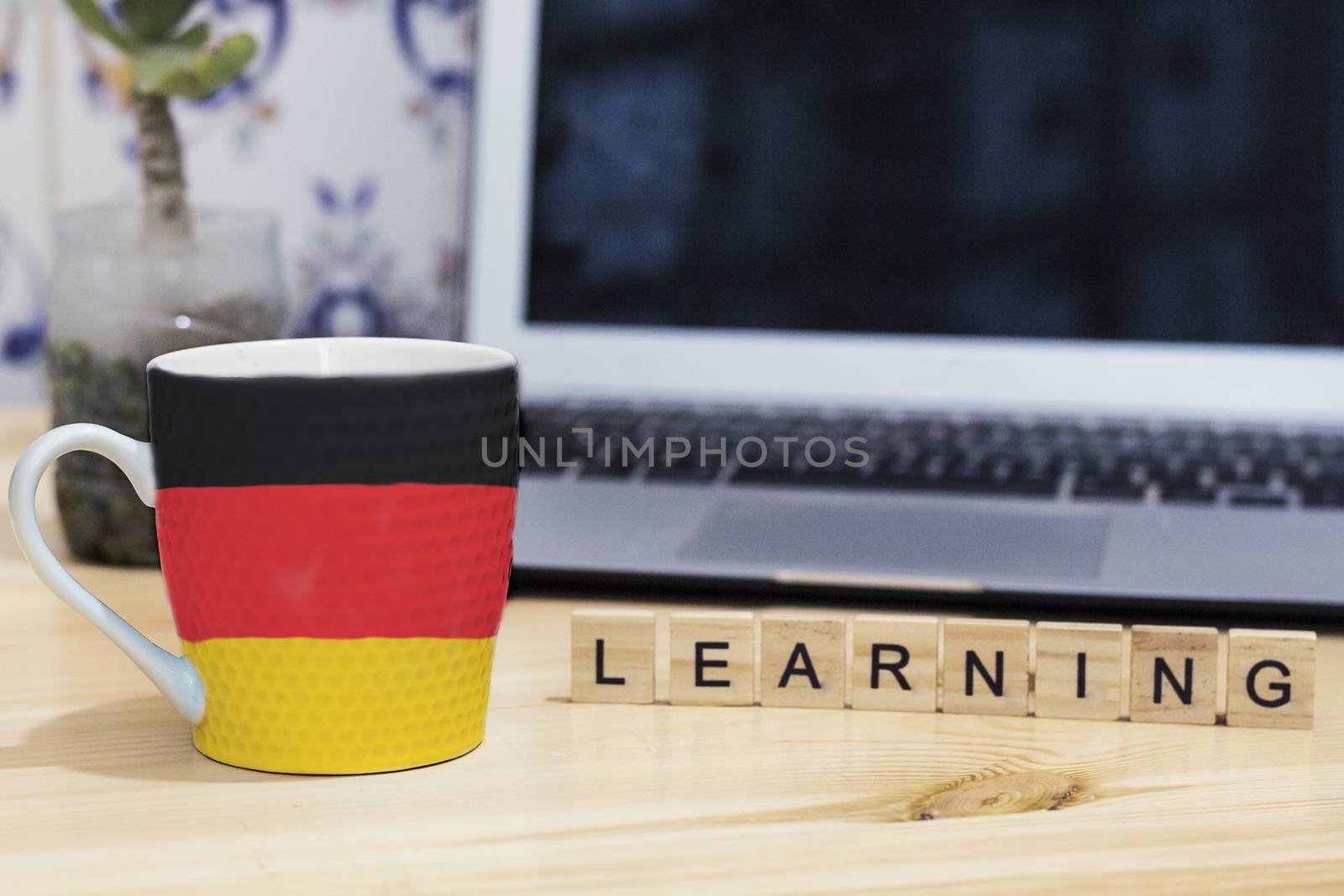 Germany  flag painted on cup coffee, letter wood learning,gray laptop