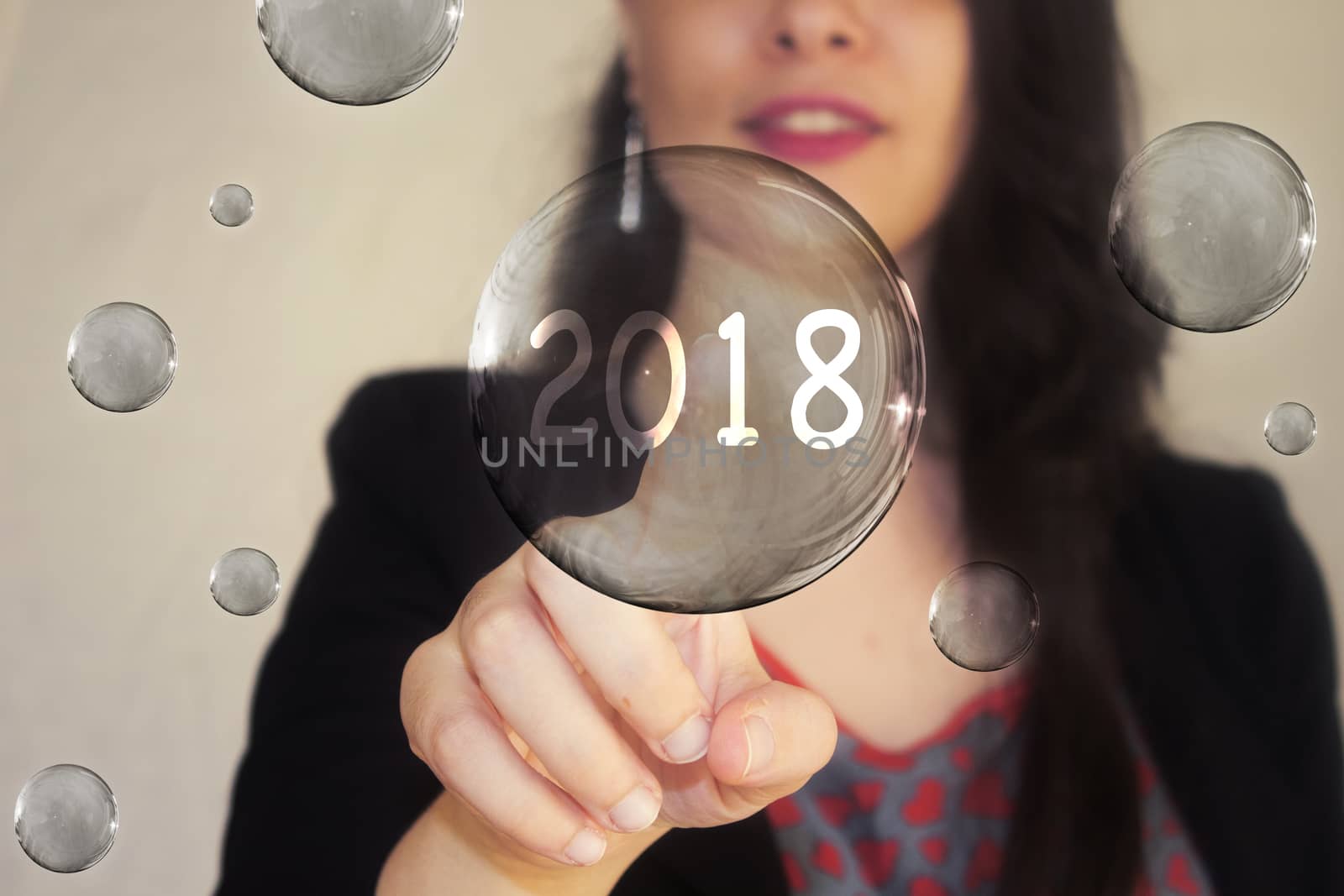 Portrait of a beautiful young woman pointing her finger to number 2018 in transparent bubble by sigoisette